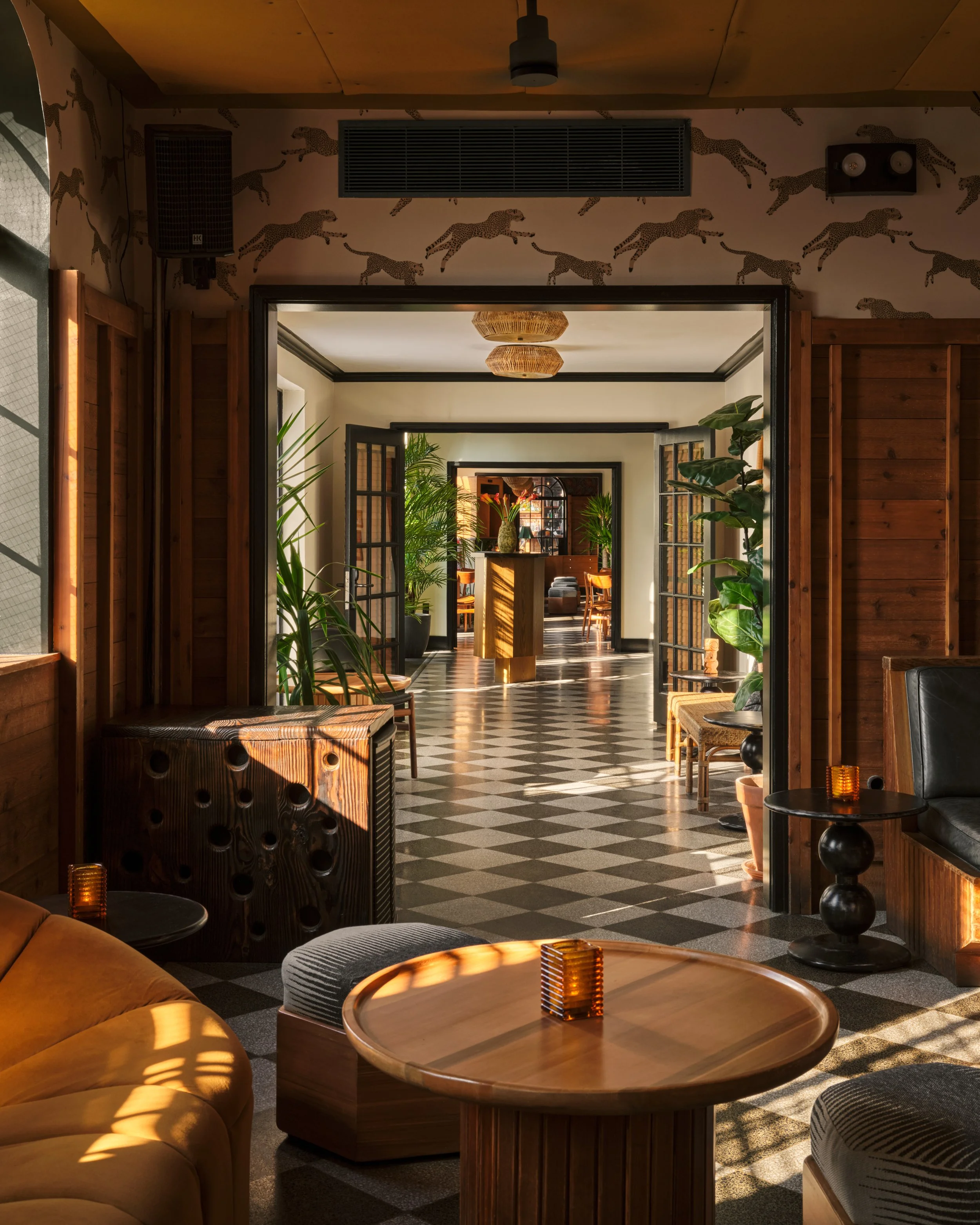 Interior of the stylish rooftop lounge at Broken Shaker NYC with mid-century modern furniture, patterned flooring, potted plants, and warm lighting.