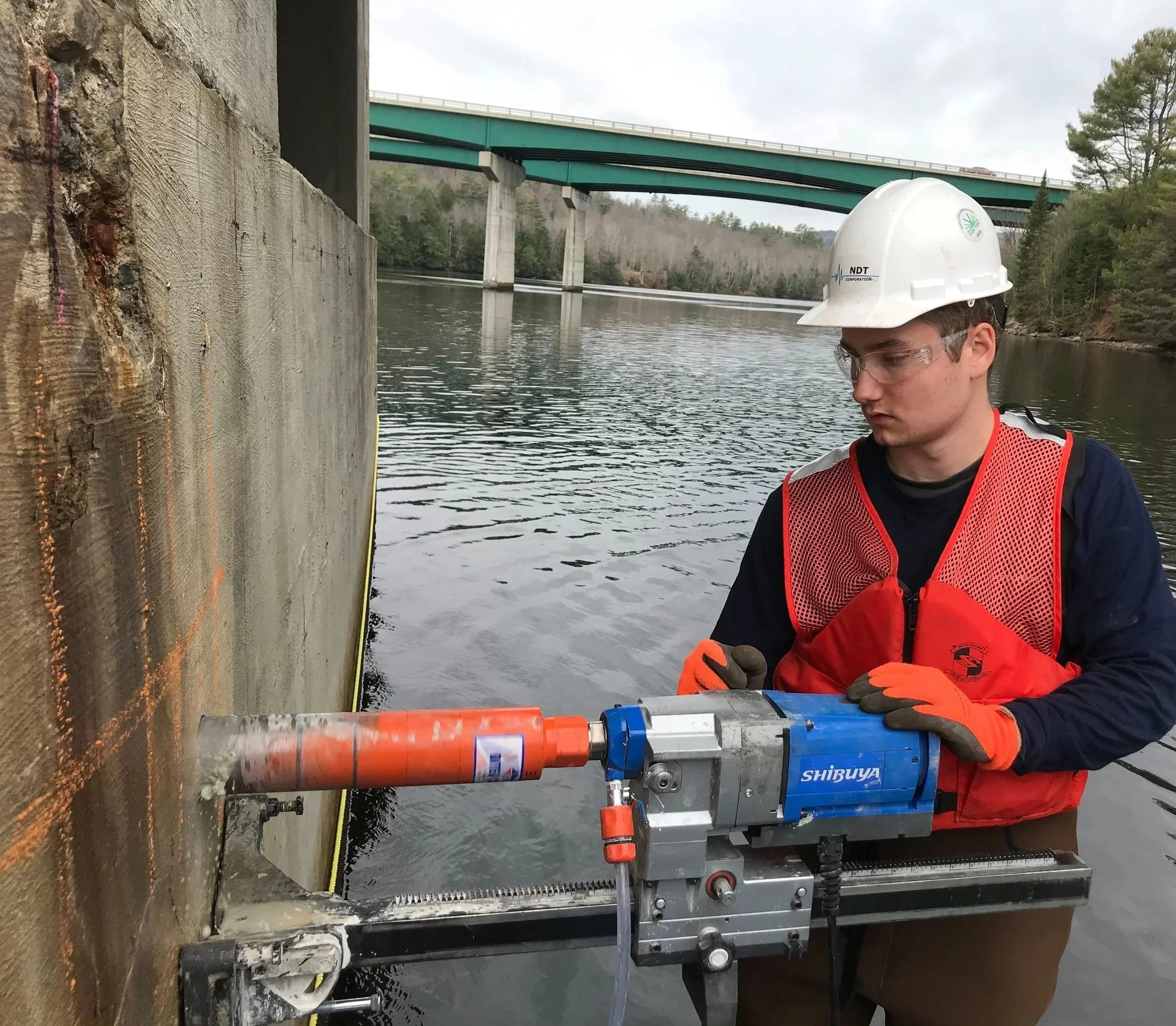 NDT technician performing a concrete core extraction on submerged bridge pier.