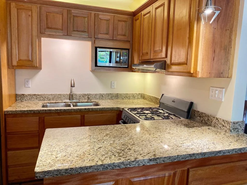 Kitchen with wooden cabinets, granite countertops, a double sink, a built-in microwave, and a gas stove.