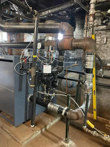 Industrial boiler system with interconnected pipes and valves in a mechanical room.