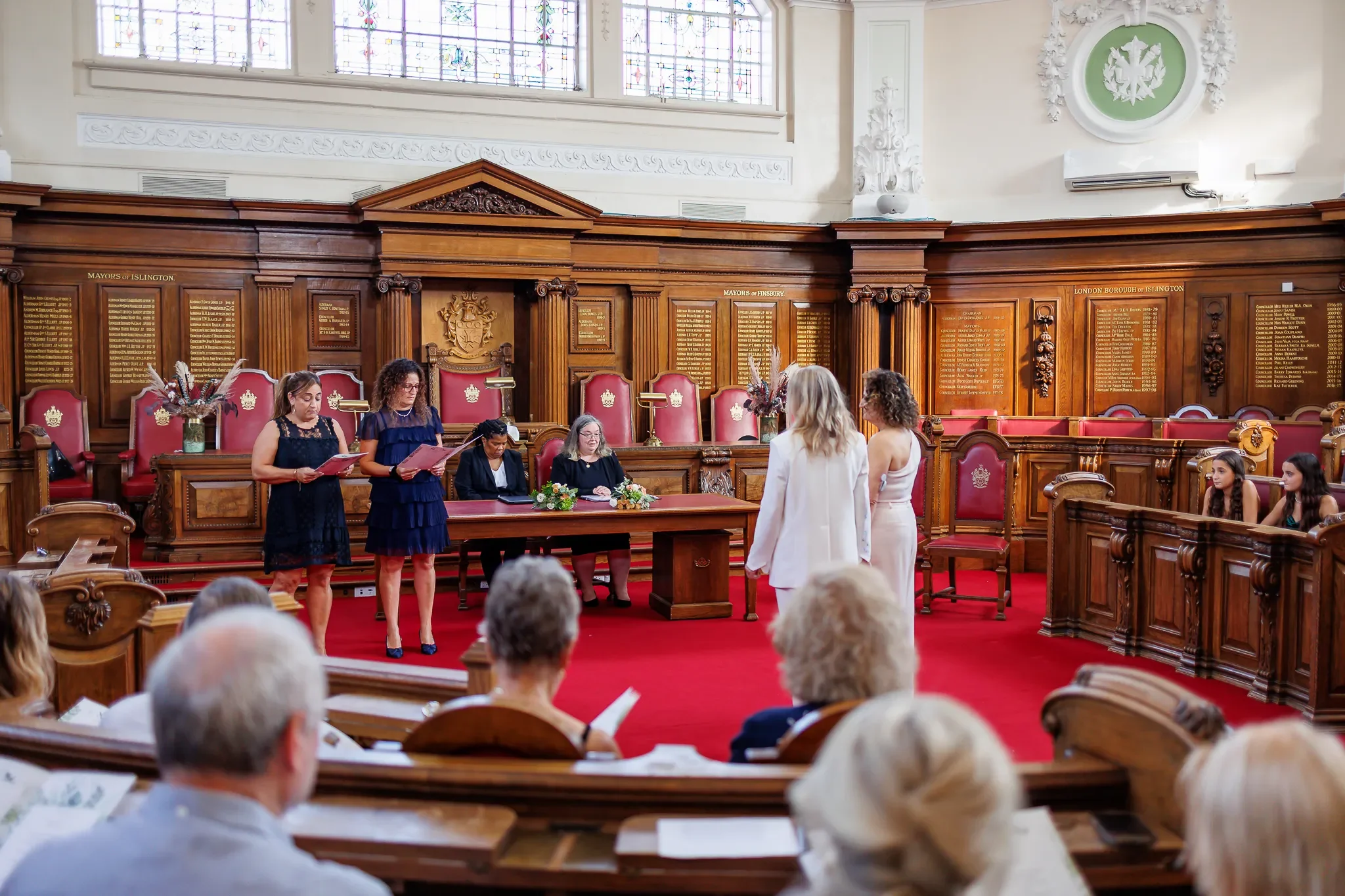 Two Brides facing registrars and readers during wedding ceremony at Islington Town Hall