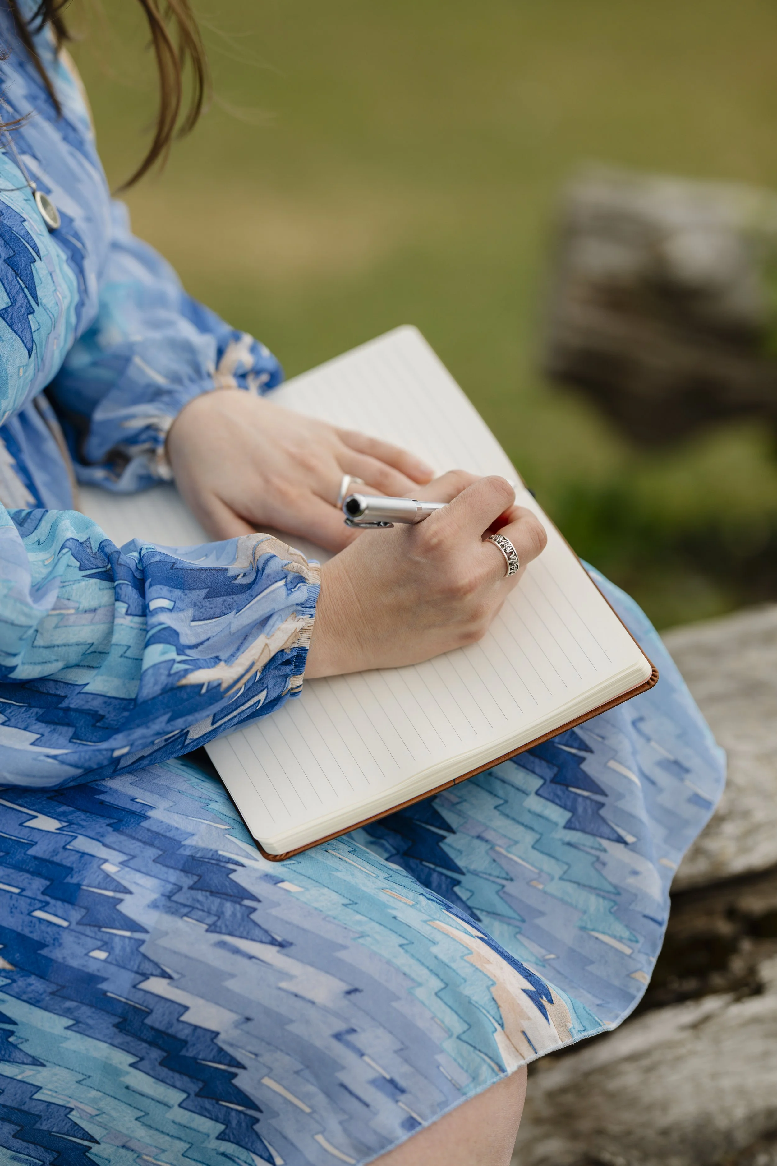 Hand holding a pen and notebook, representing reflective clinical supervision.