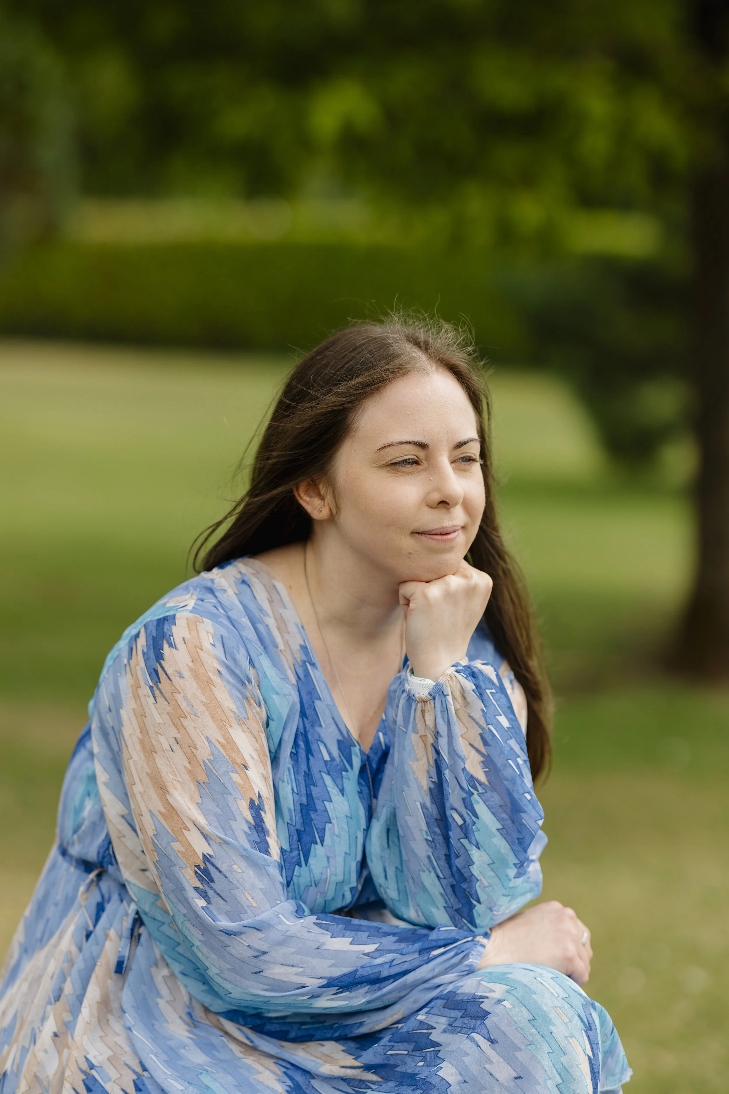 Laurie Hole, UK-based online counsellor, sitting in Poole Park and looking into the distance.