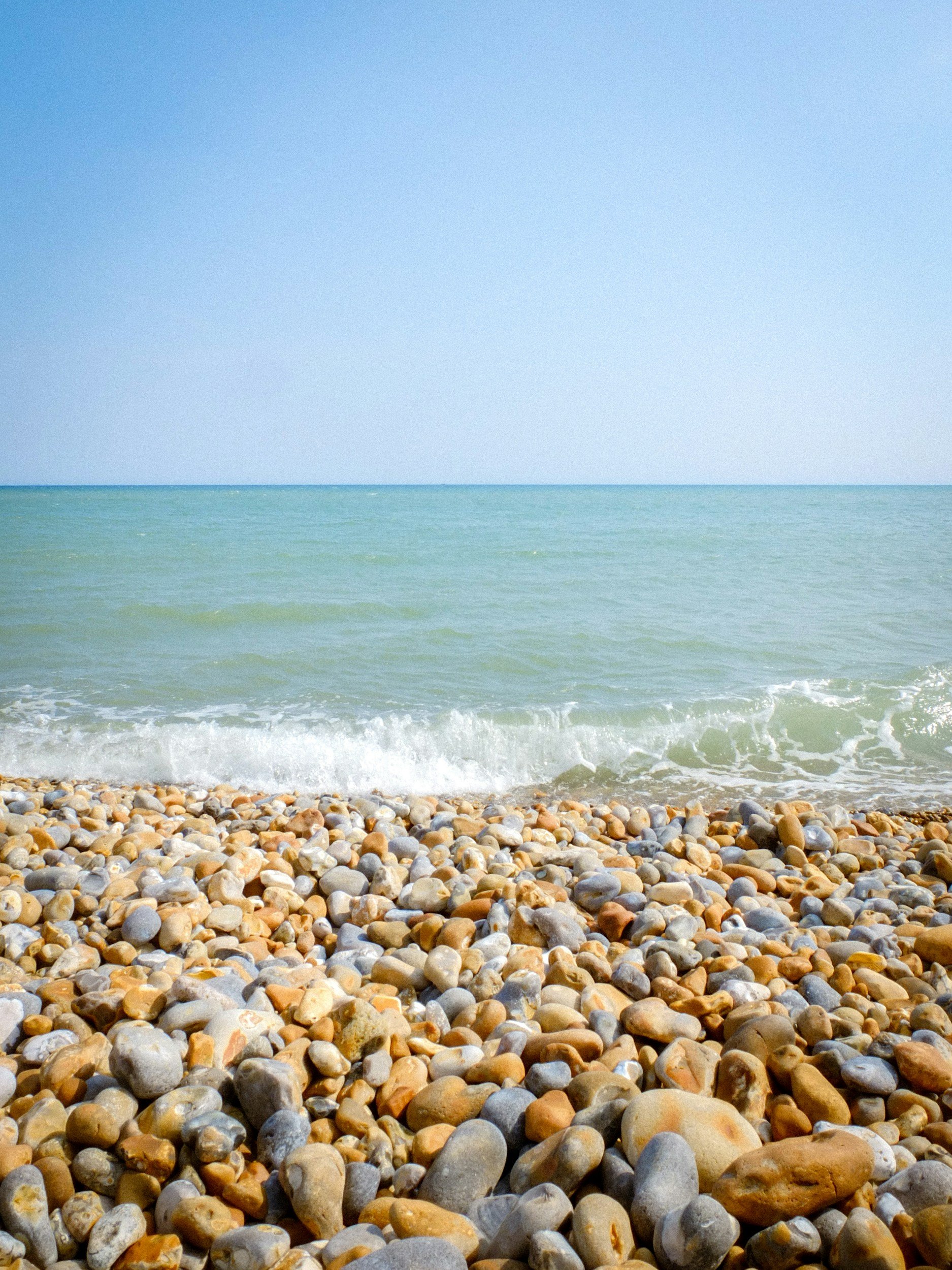 Smooth pebbles along a quiet shoreline, with gentle water washing over the stones.
