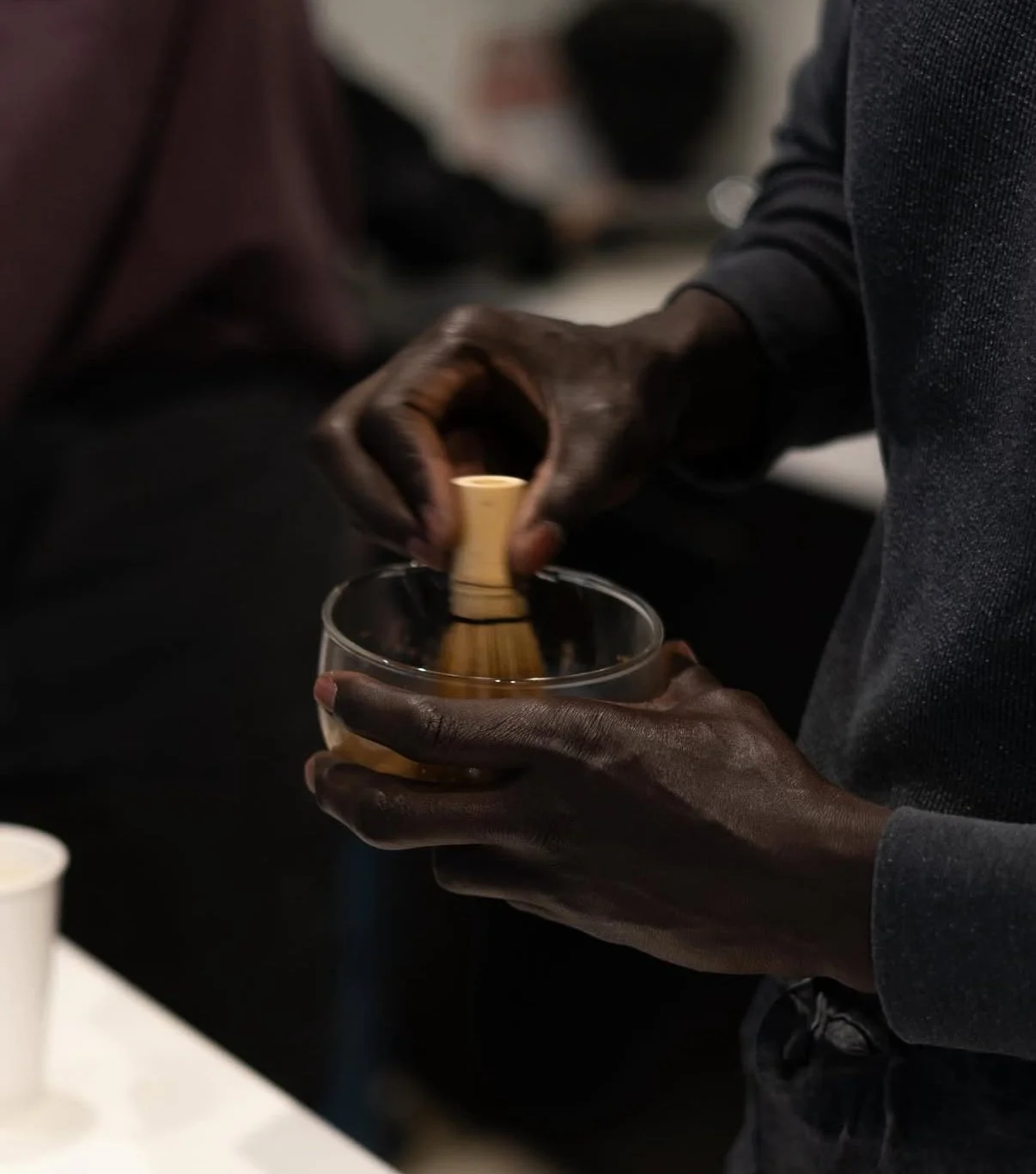 Person holding a glass and using a tool to stir a drink.