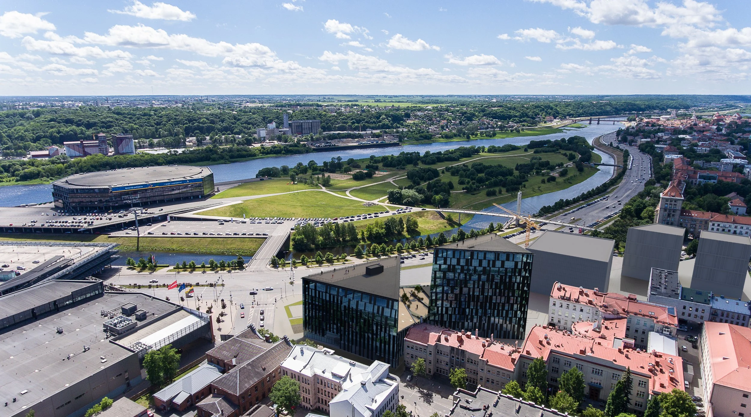 Aerial view of a cityscape with buildings, a river, and green parks under a partly cloudy sky.