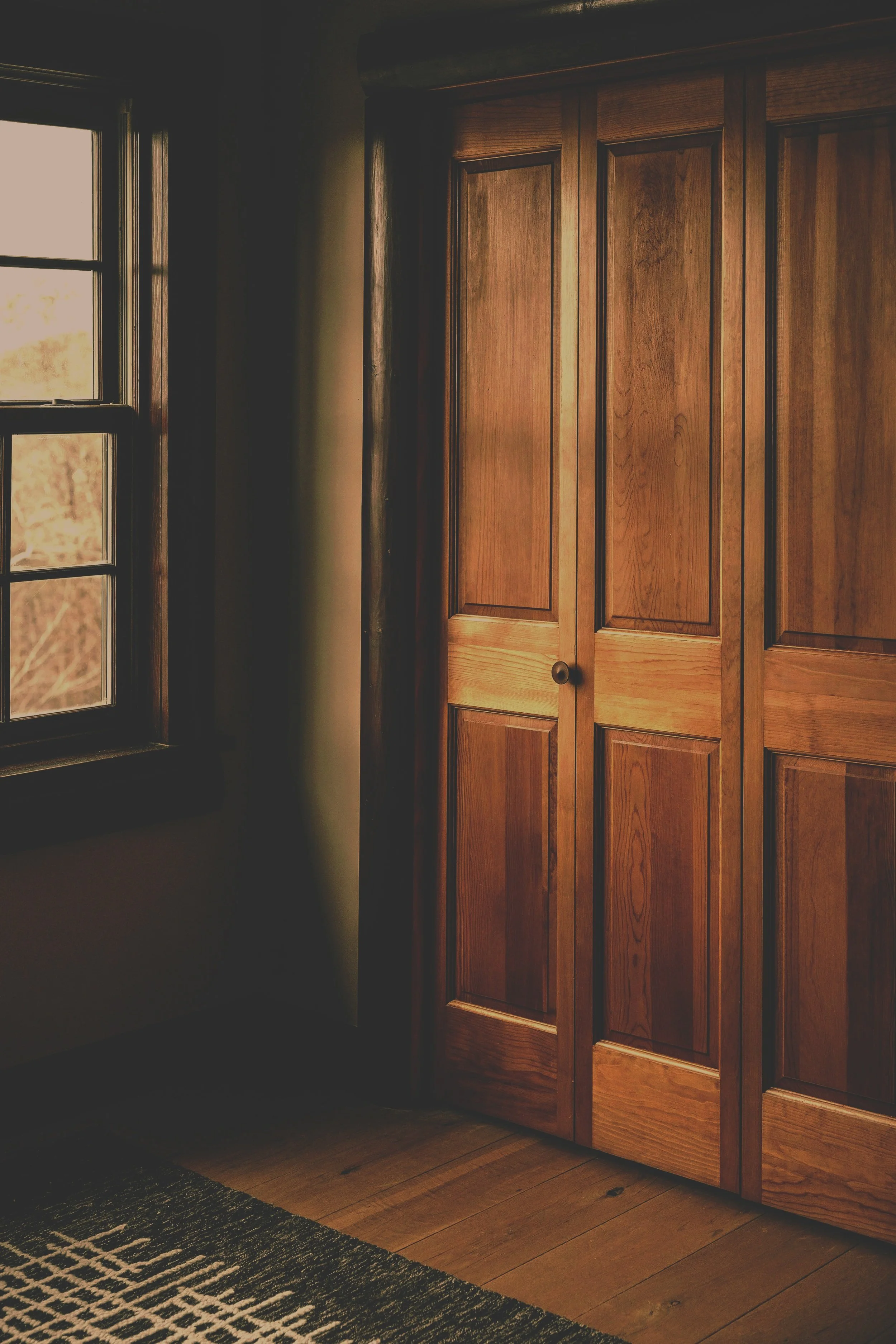 A room with a wooden closet and a window with natural light coming in.