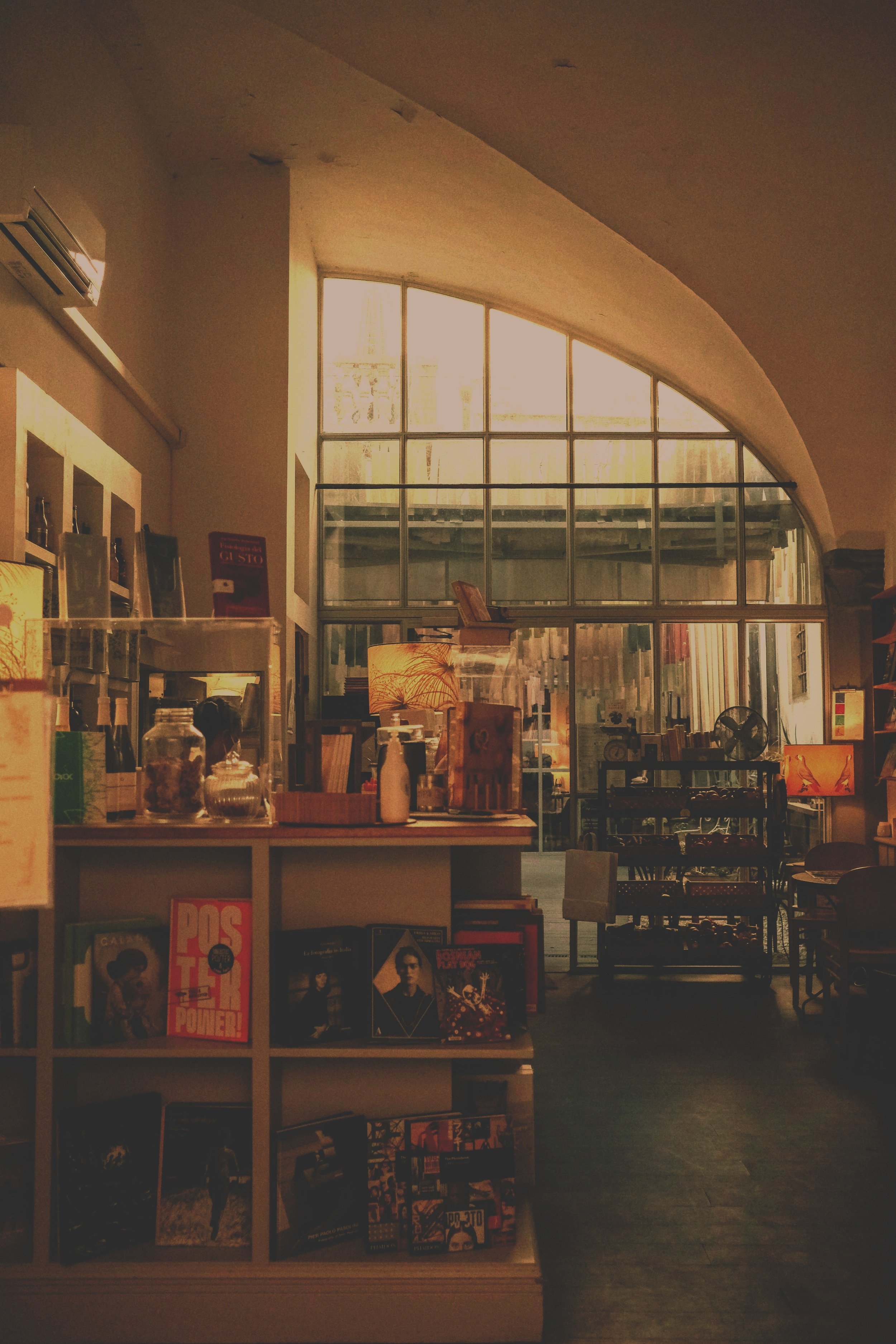 Interior of a cozy bookstore with warm lighting, bookshelves, and large window letting in natural light.
