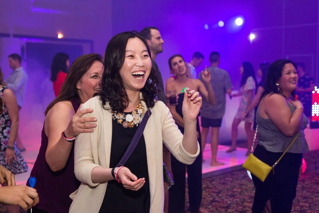 People dancing and having fun at a party with purple and pink lighting.