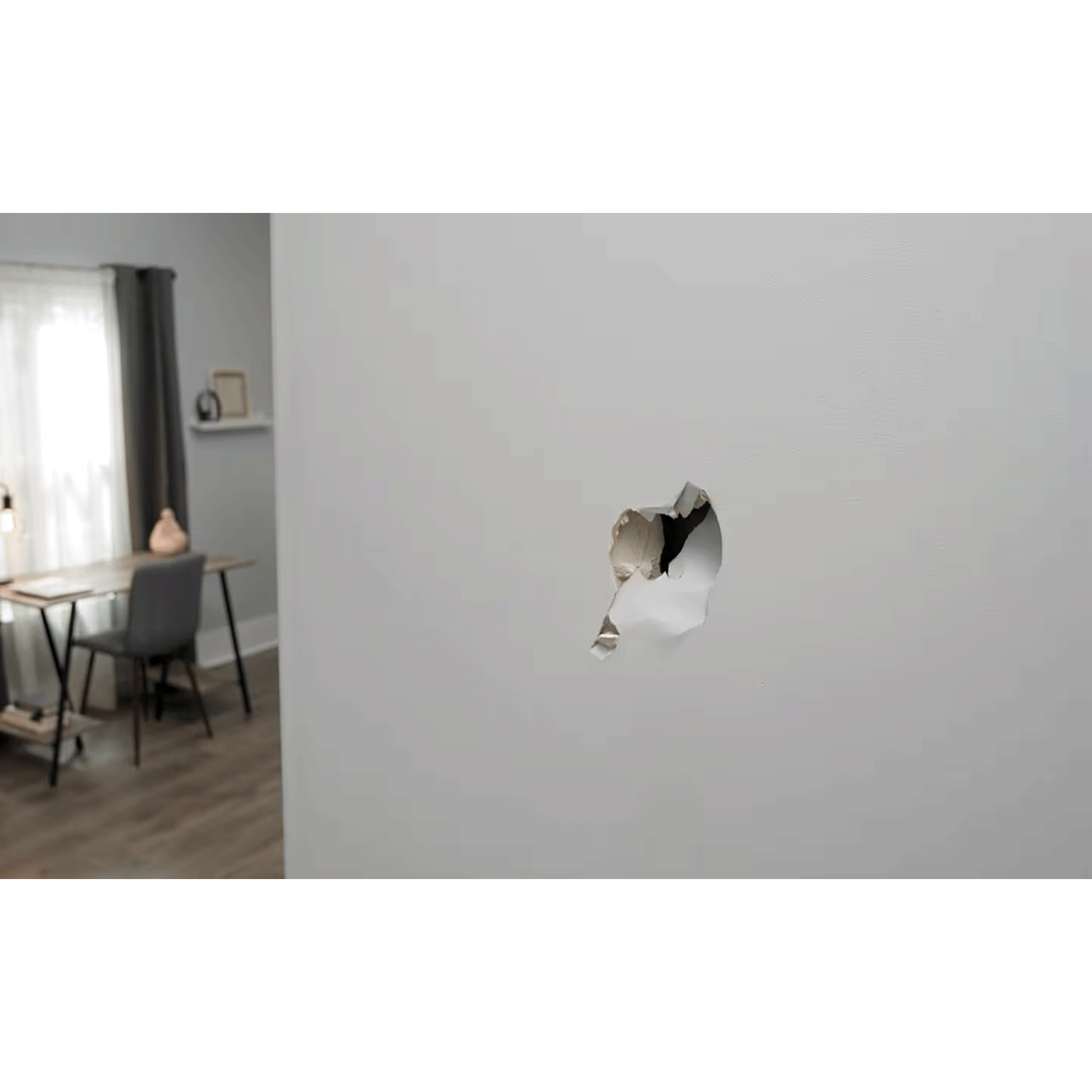 Hole in a white wall with a room visible in the background, including a table, chairs, and window with curtains.