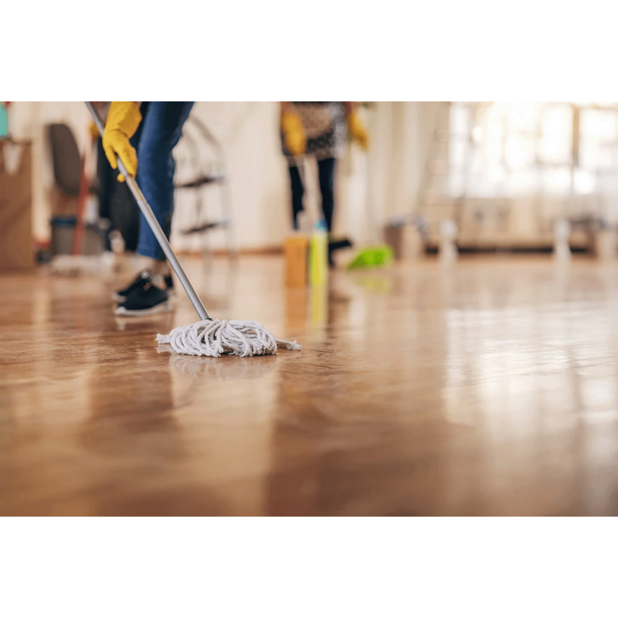 People cleaning a wooden floor with mops and cleaning supplies in a bright room.