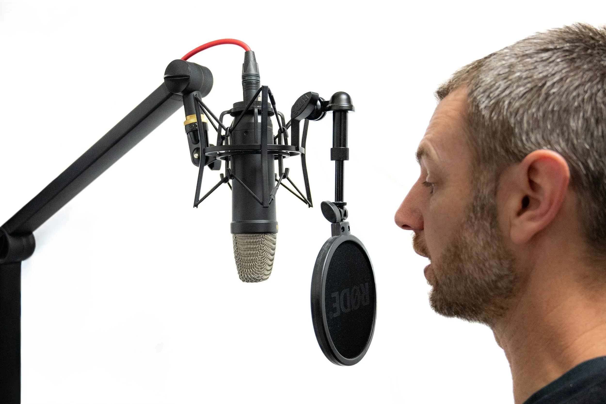 Man recording voice with a microphone in a studio.