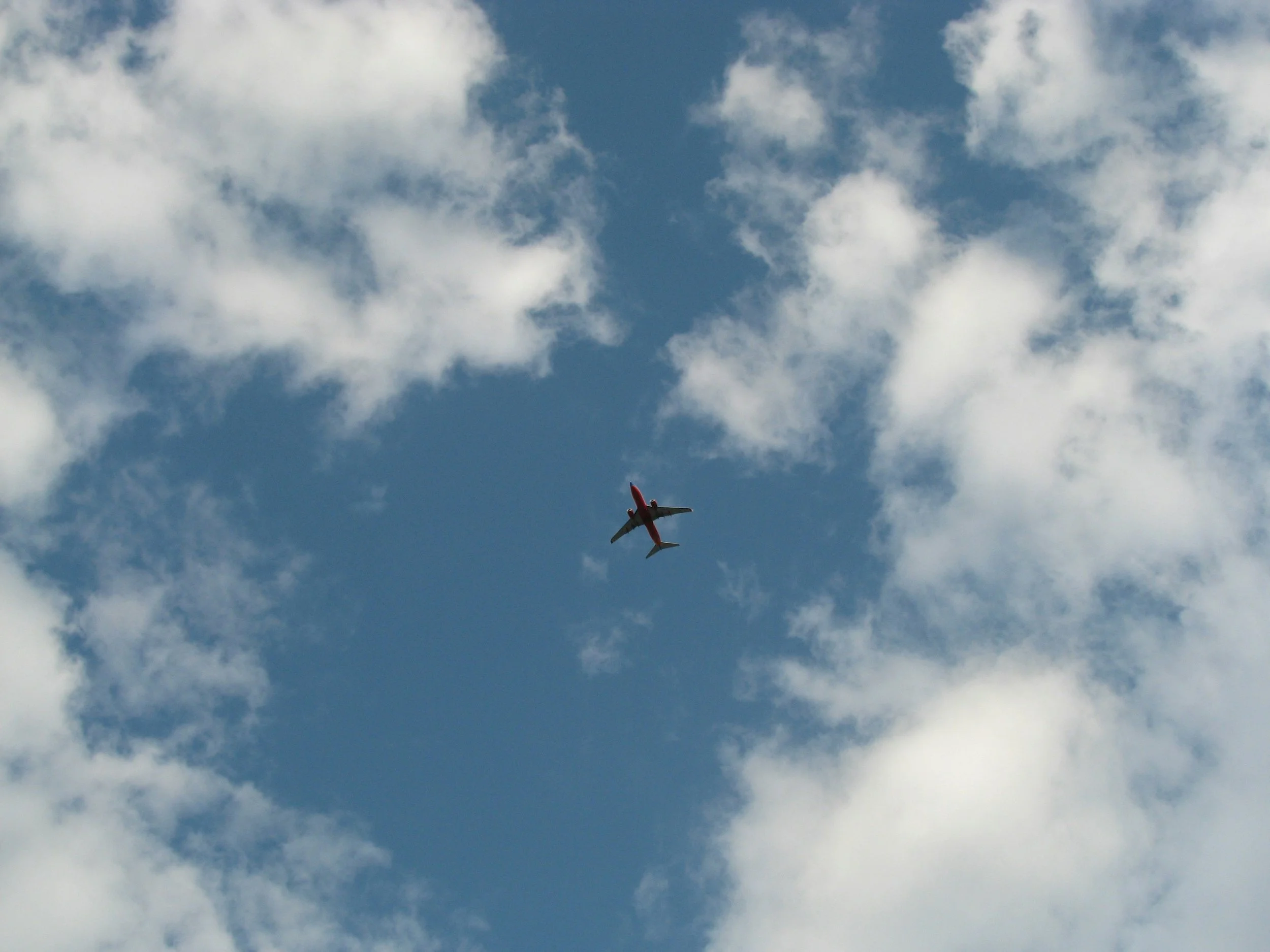 A plane flying high in the sky amidst white clouds.
