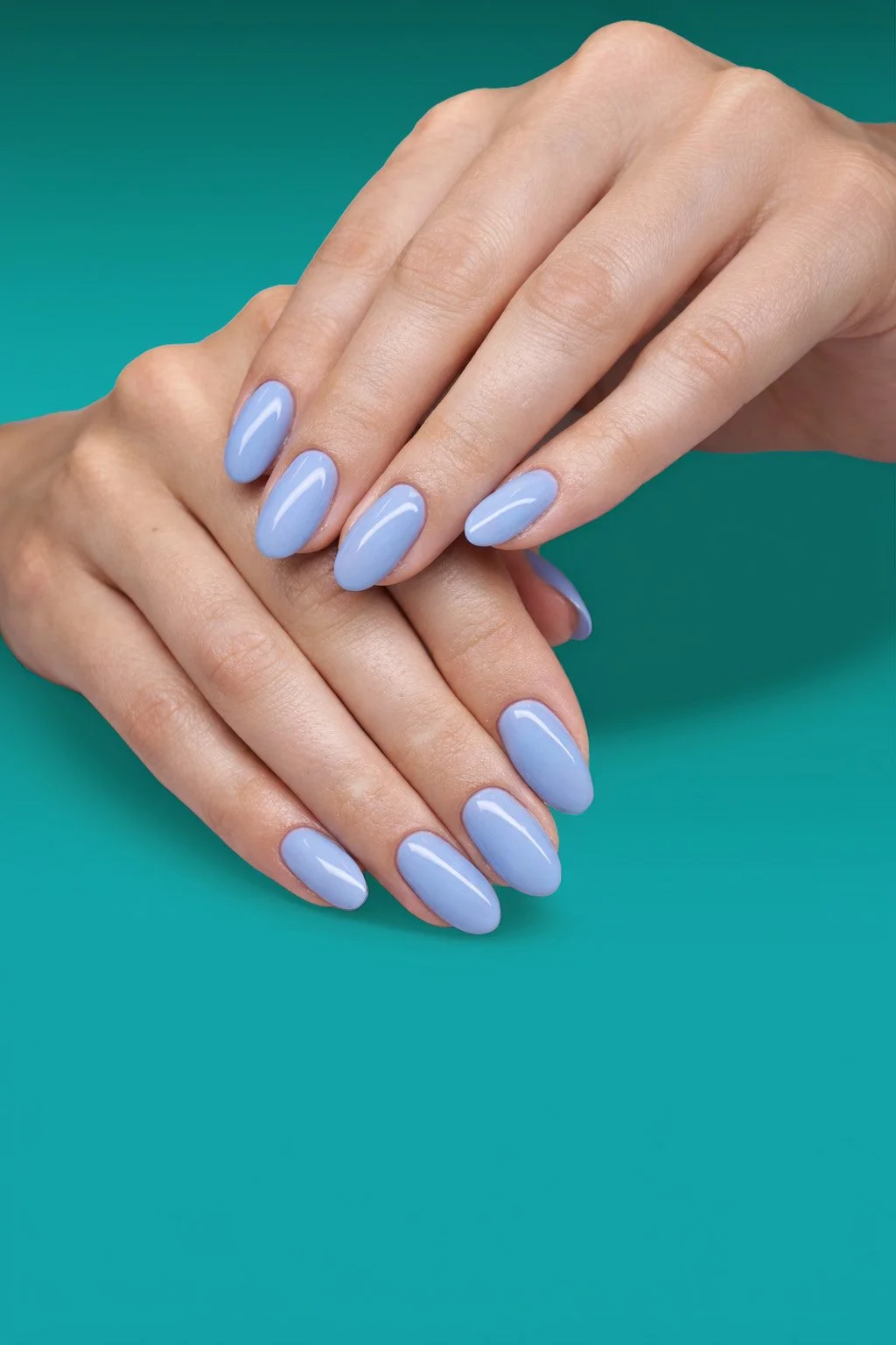 Close-up of hands with light blue manicured nails resting on a teal surface.