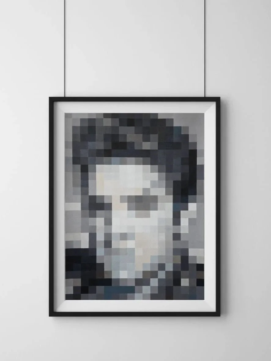 Pixelated black-and-white portrait photograph in a black frame hanging on a white wall.