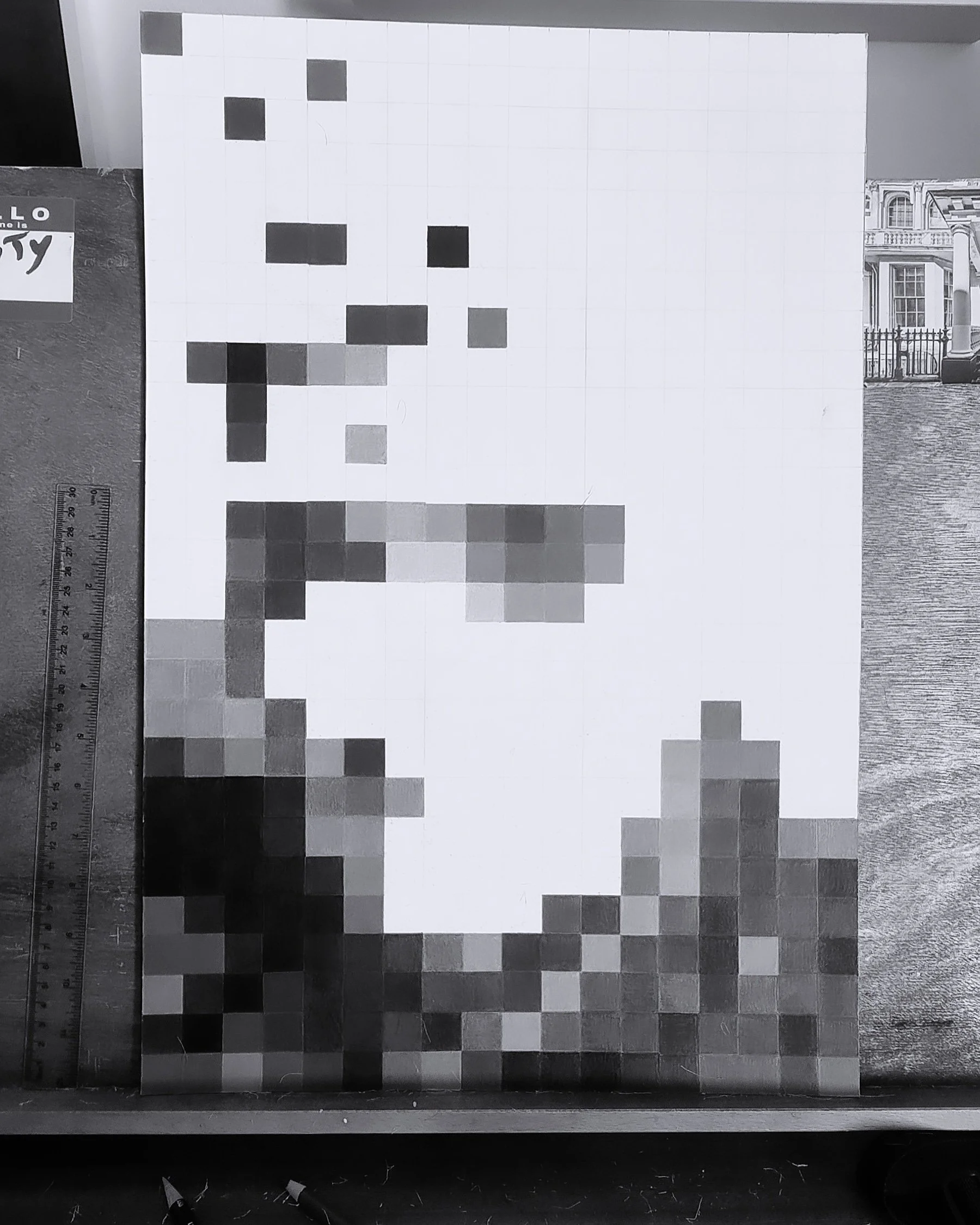 A pixelated grayscale image of Marilyn Monroe's face on graph paper with a ruler on the left side.