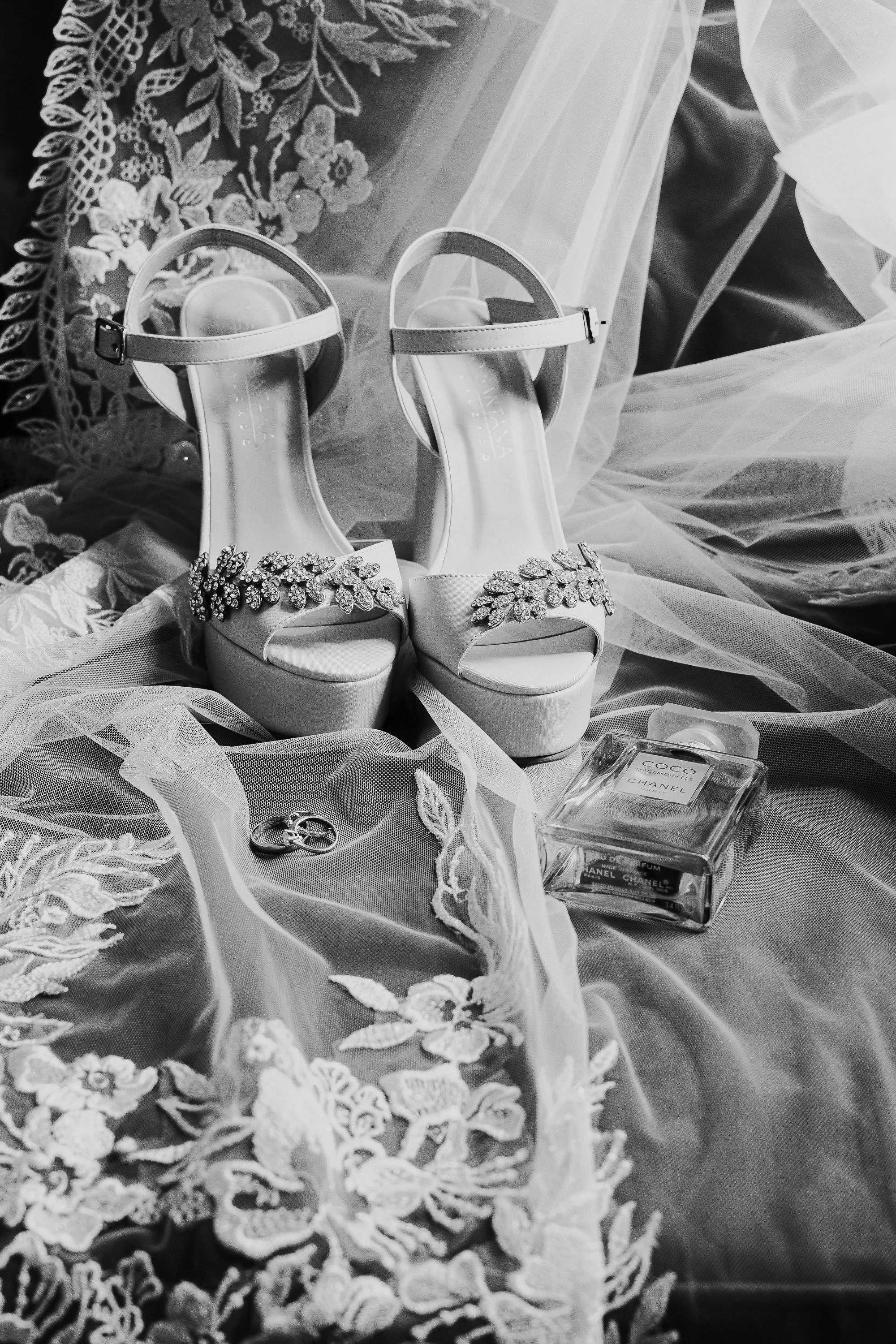 Wedding shoes, ring, and perfume on lace fabric.