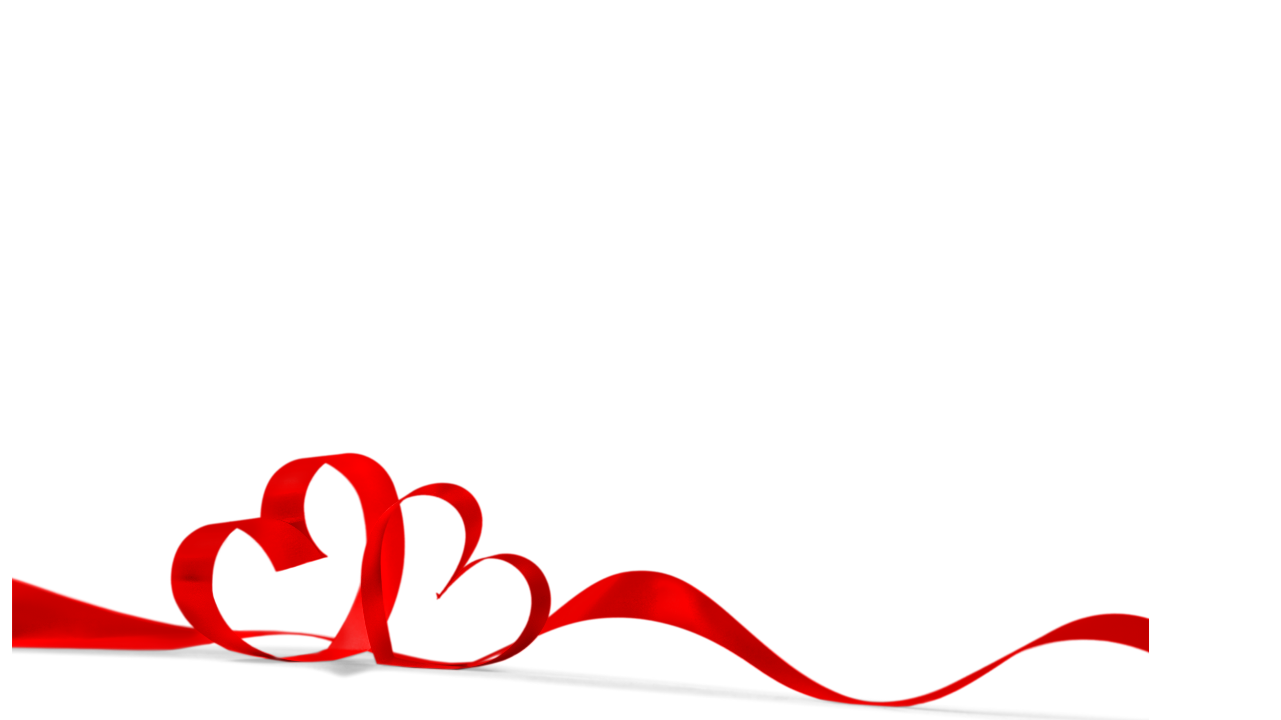 A red ribbon decorated with two heart-shaped loops, resting on a dark surface with a slight reflection. The background is black.