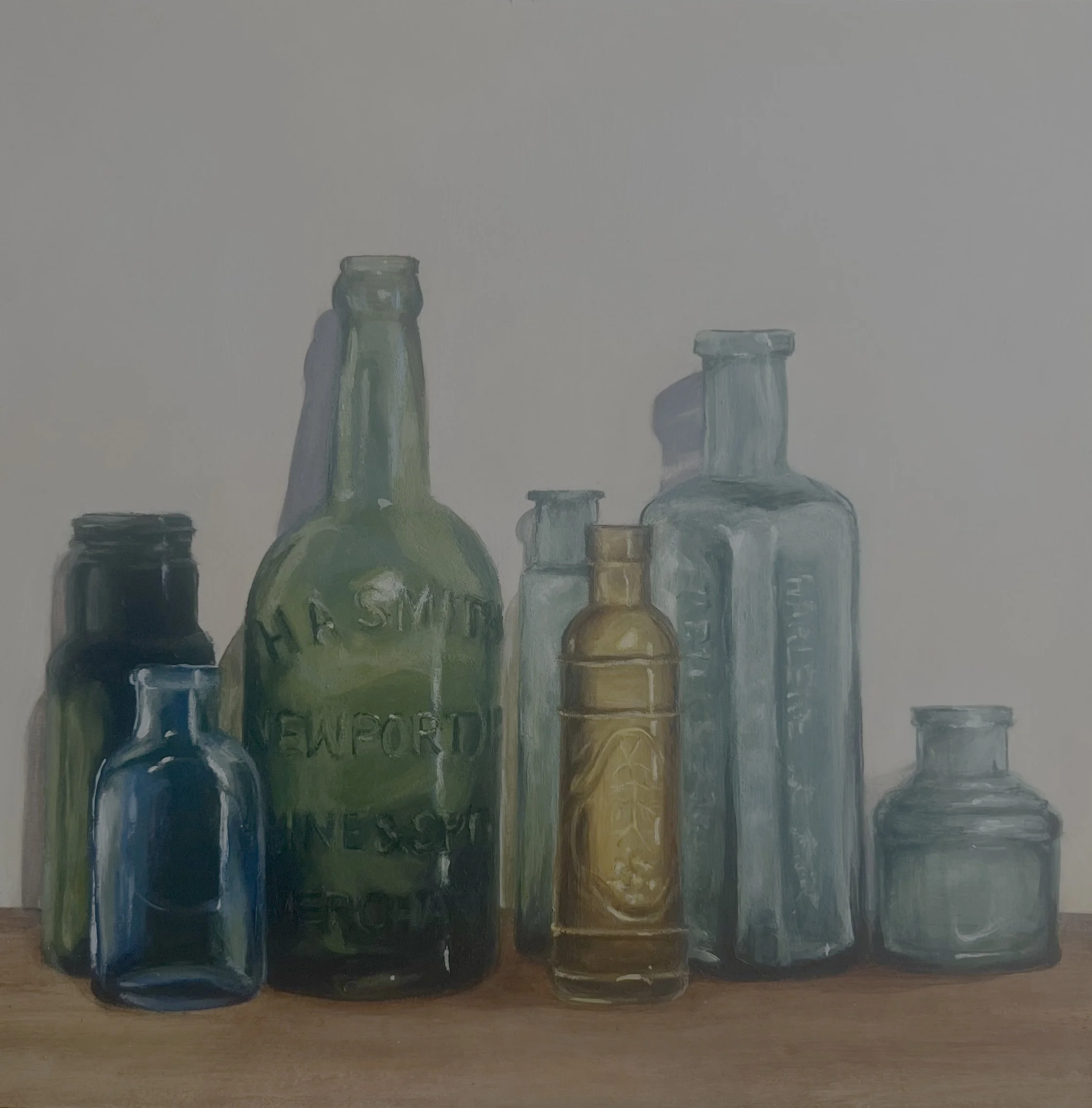 Collection of vintage glass bottles in various sizes and colors on a wooden surface.