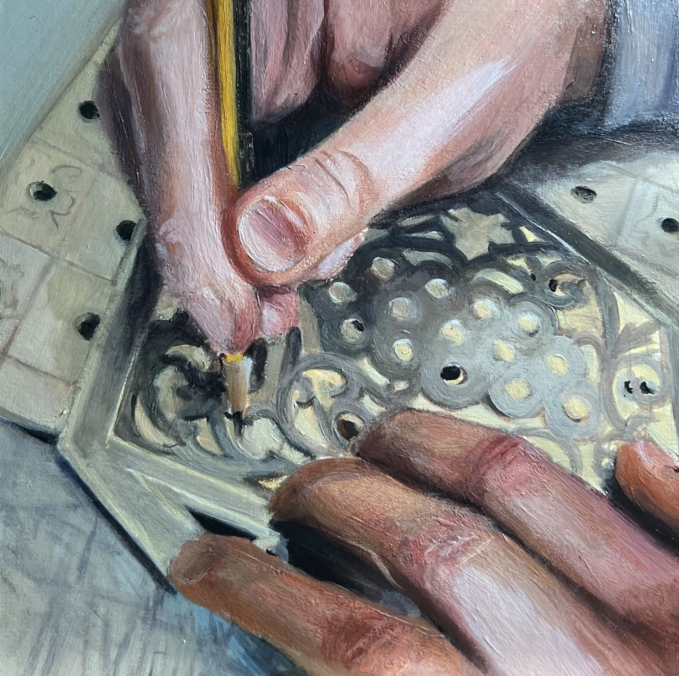 Close-up of a person's hands engraving a decorative metal object with a fine tool.