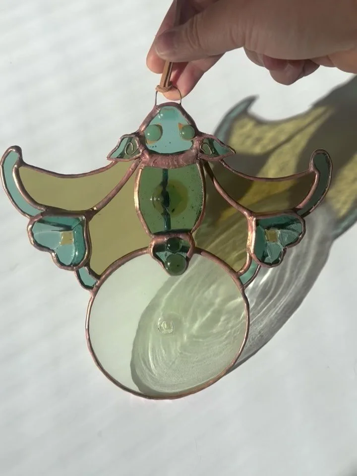 This inverted stained glass bat, clutching a glass rondel, draws from the iconic neon signs of Hong Kong pawn shops. In the vernacular, an upside-down bat holding a coin signals &ldquo;good fortune has arrived,&rdquo; while a bat paired with an ancie