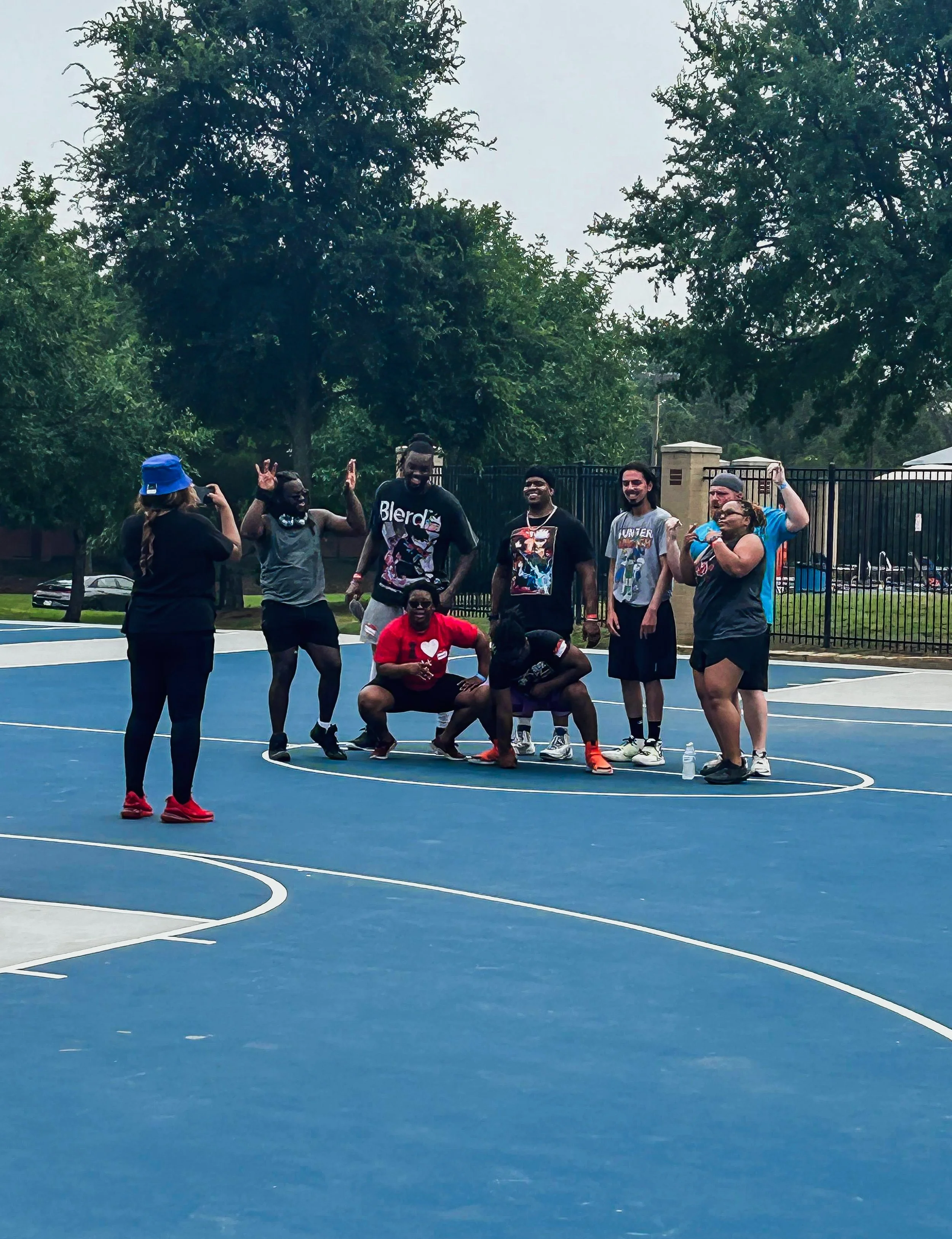 Group of people posing for a photo on an outdoor basketball court during daytime.