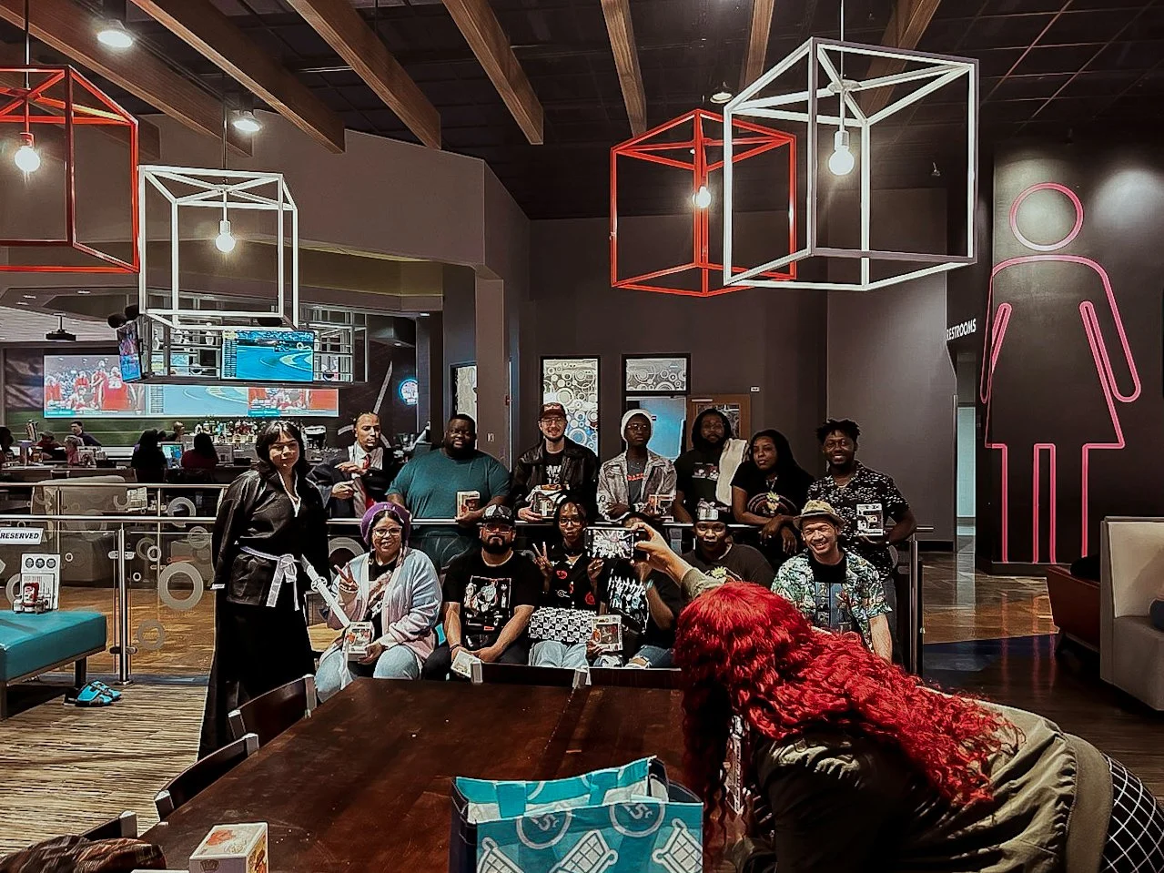 A group of people posing for a photo inside a restaurant with modern decor and geometric hanging light fixtures.