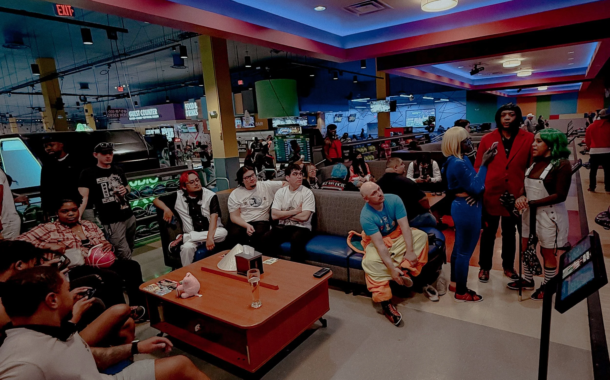 People dressed in cosplay, in a bowling alley with lanes, video screens, and arcade machines in the background.
