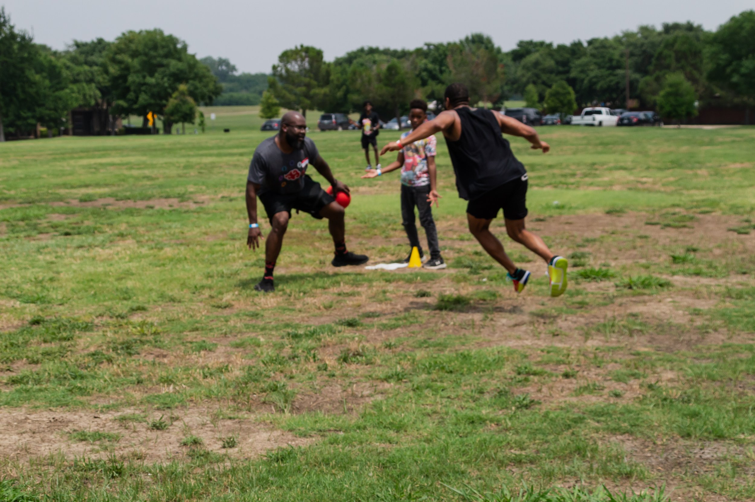 Two men playing a game on a grassy field while a young boy watches.