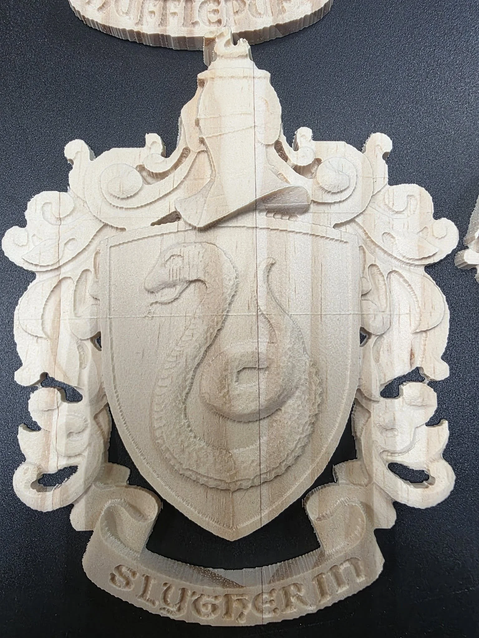 A wooden shield-shaped plaque with a carved face, decorative scrollwork, and the word 'SLUGGER' inscribed at the bottom.