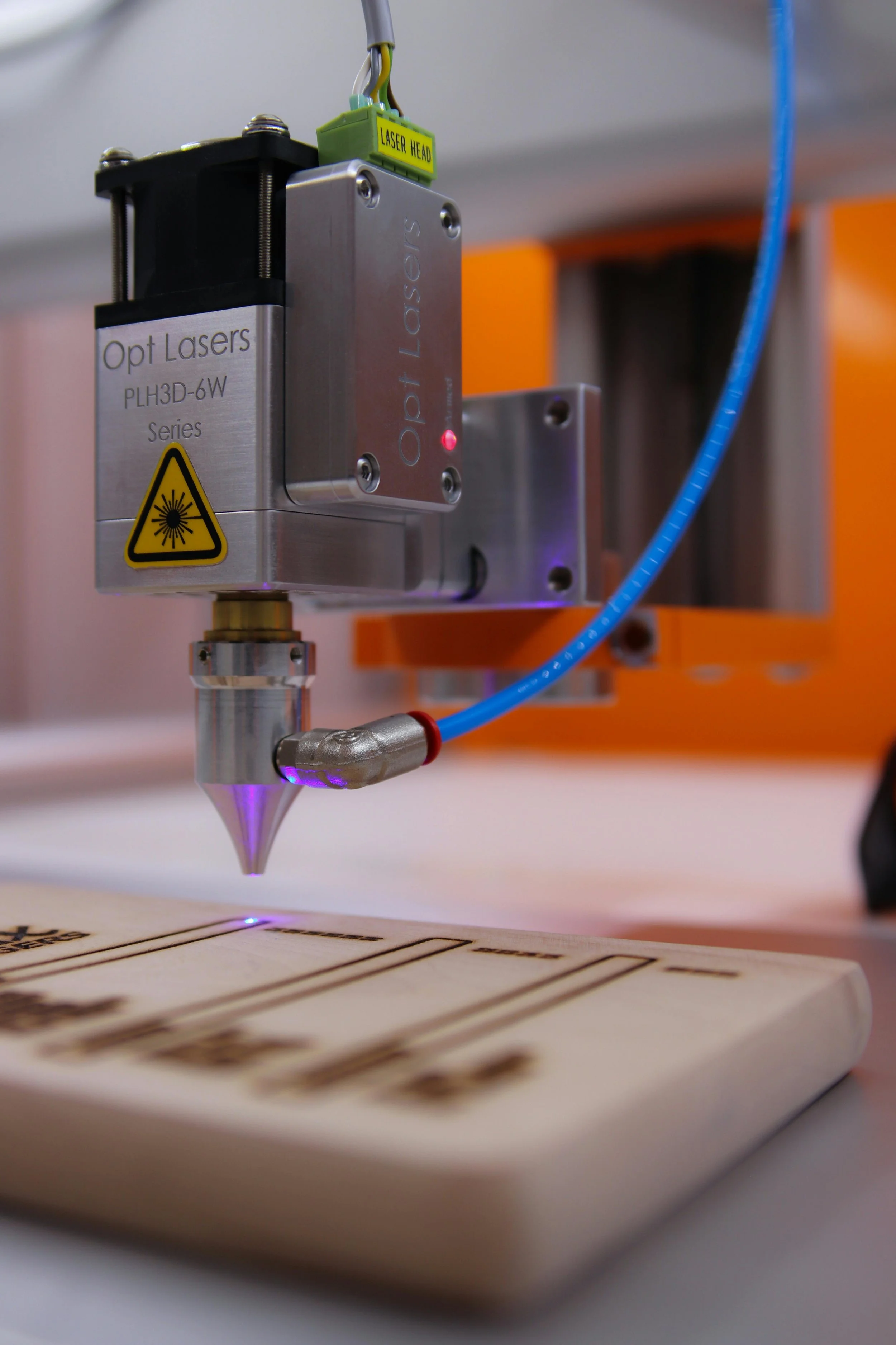 A laser engraving machine etching text onto a rectangular wooden object.