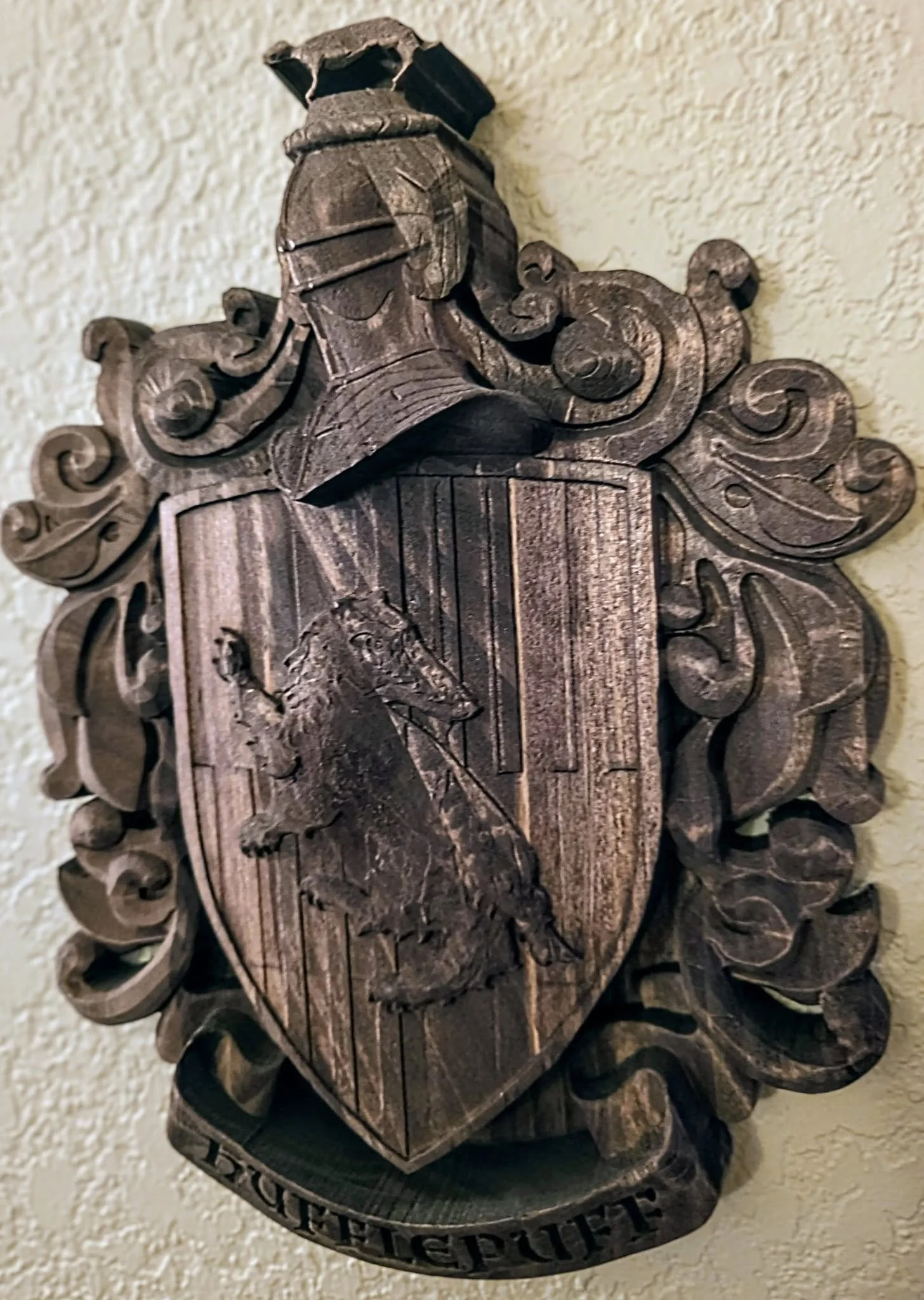 Wooden coat of arms with a shield featuring a horse's head and a knight's helmet on top, surrounded by decorative scrollwork, with a banner reading 'ROTE GUTTE' at the bottom.