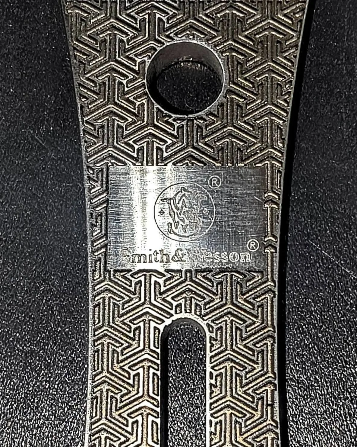 Close-up of stainless steel knife with laser engraved geometric patterns.