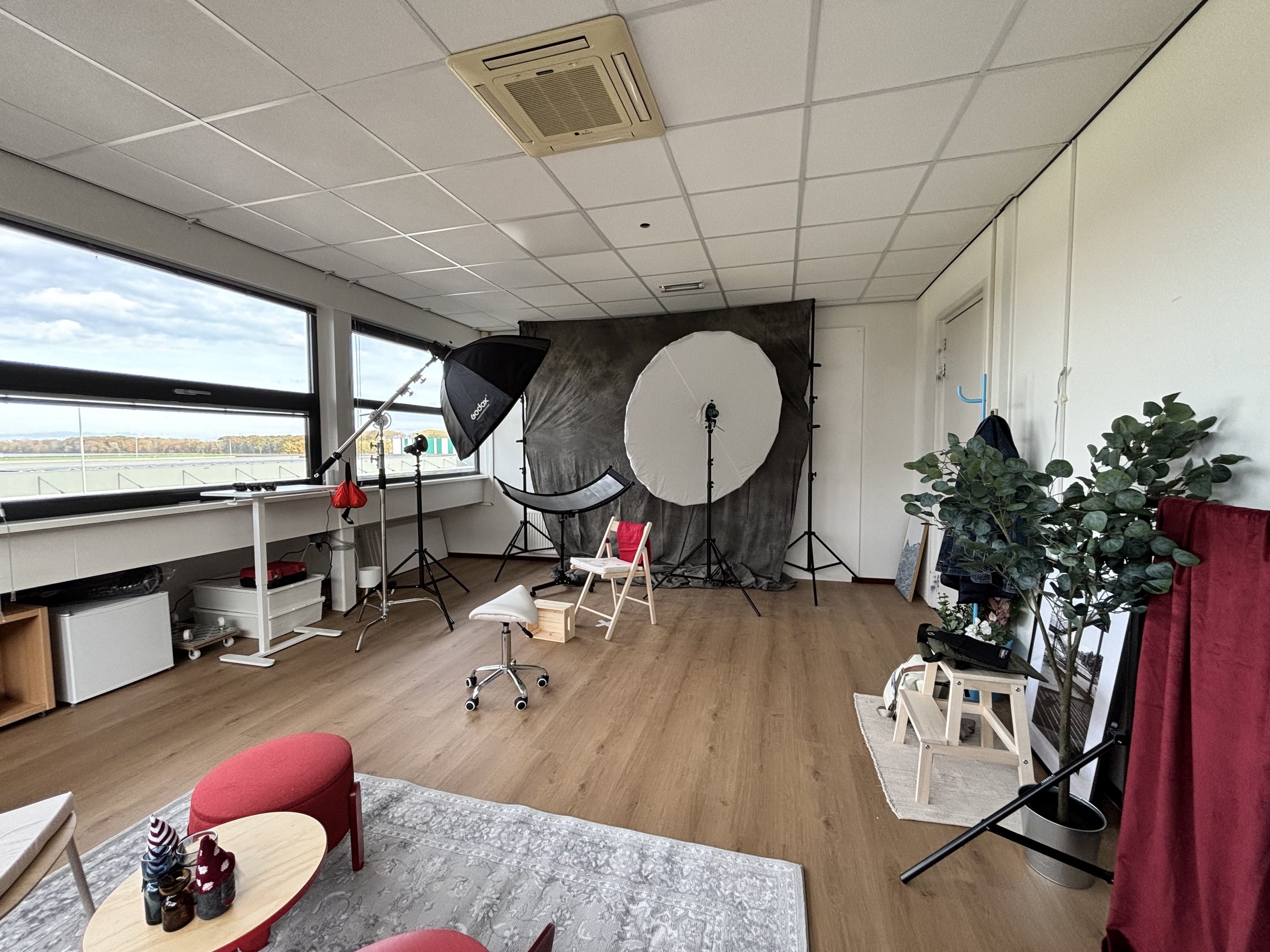 Mijn fotostudio met achtergrond, softbox verlichting, fotografische accessoires en planten, ingericht voor fotoshoots.