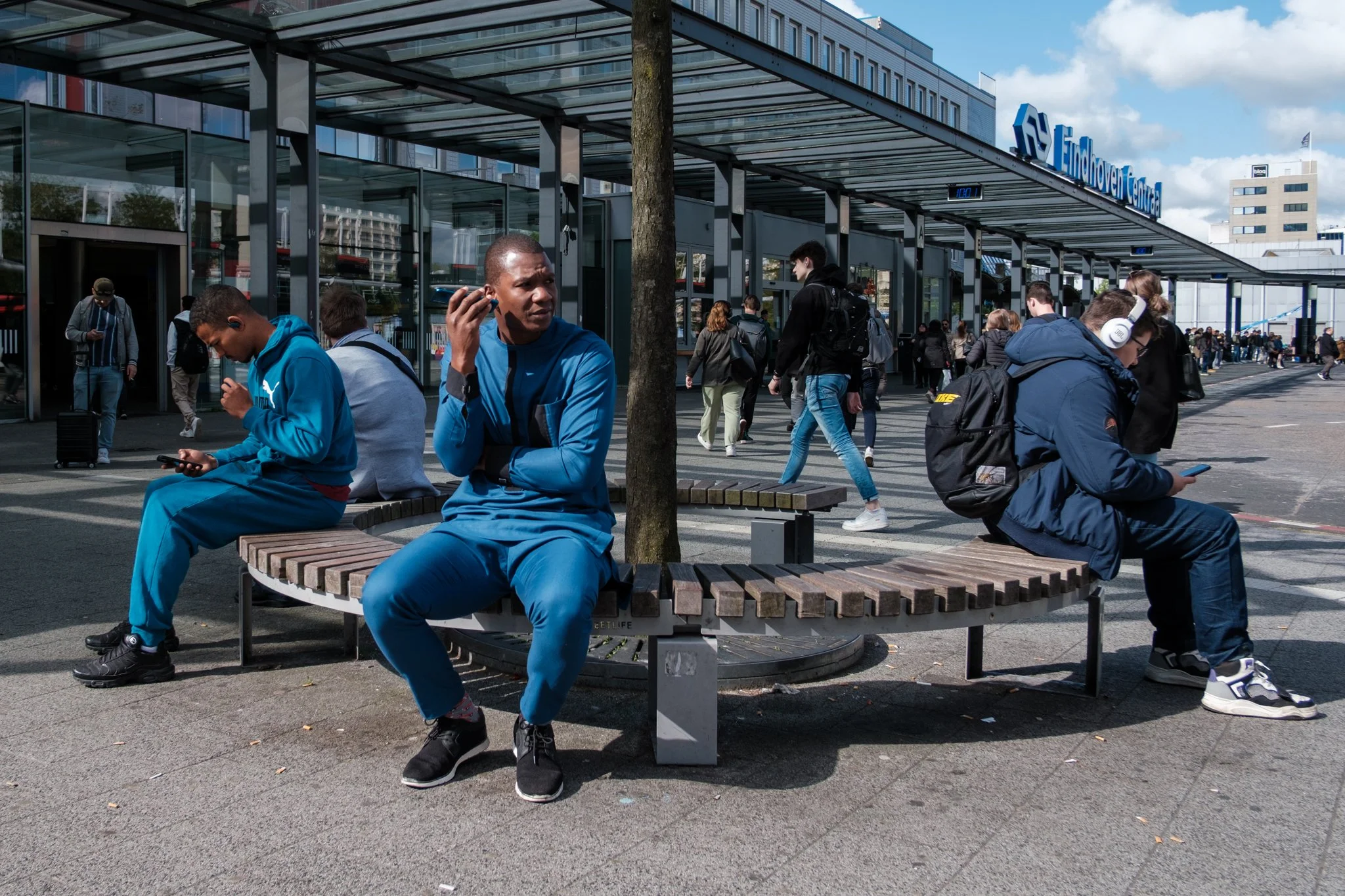Mensen wachten op een trein of bus bij het centraal station in Eindhoven, Nederland, terwijl ze gebruik maken van hun mobiele telefoons.