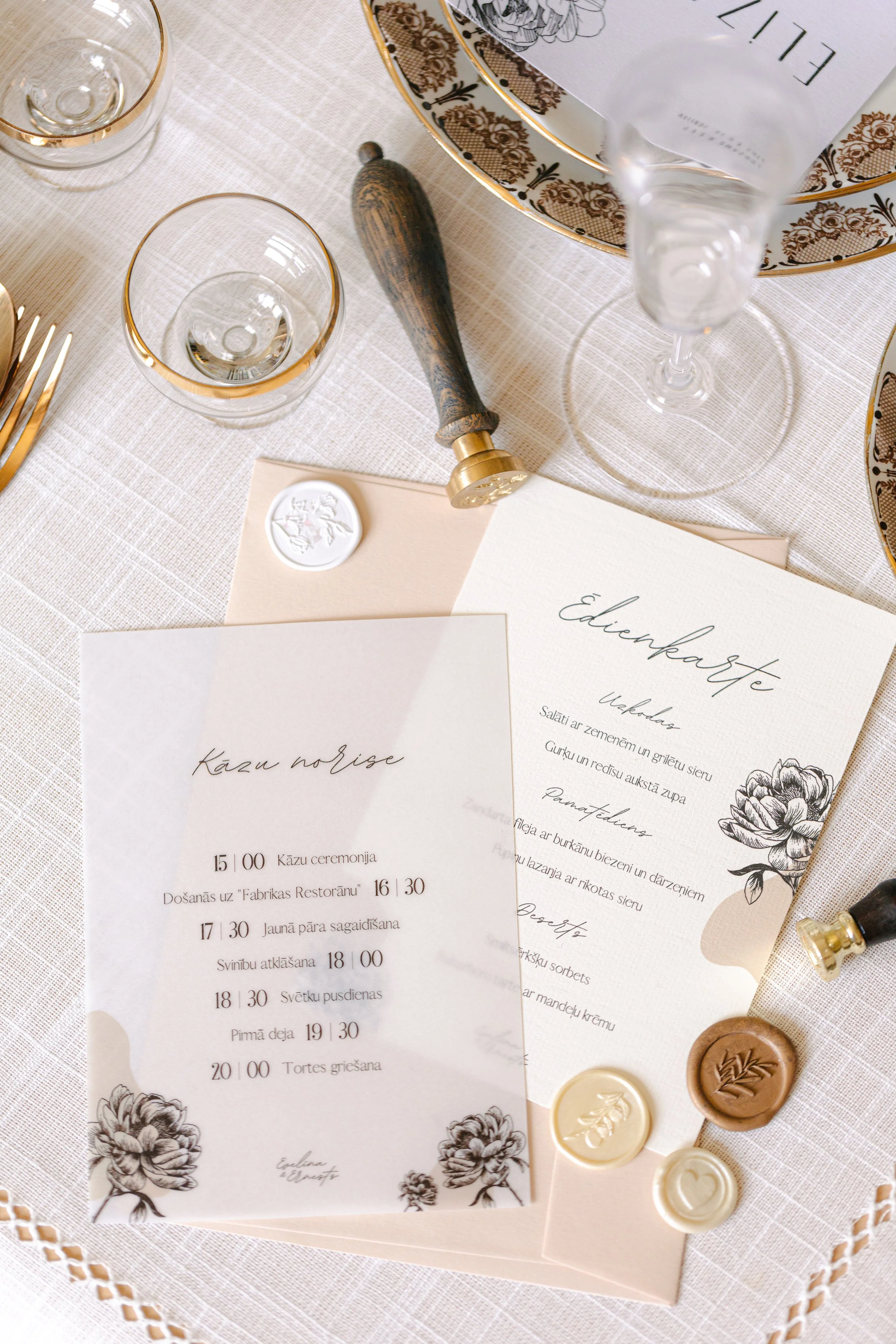 Elegant table setting with printed menus, glassware, and decorative wax seals, for a wedding or formal event.