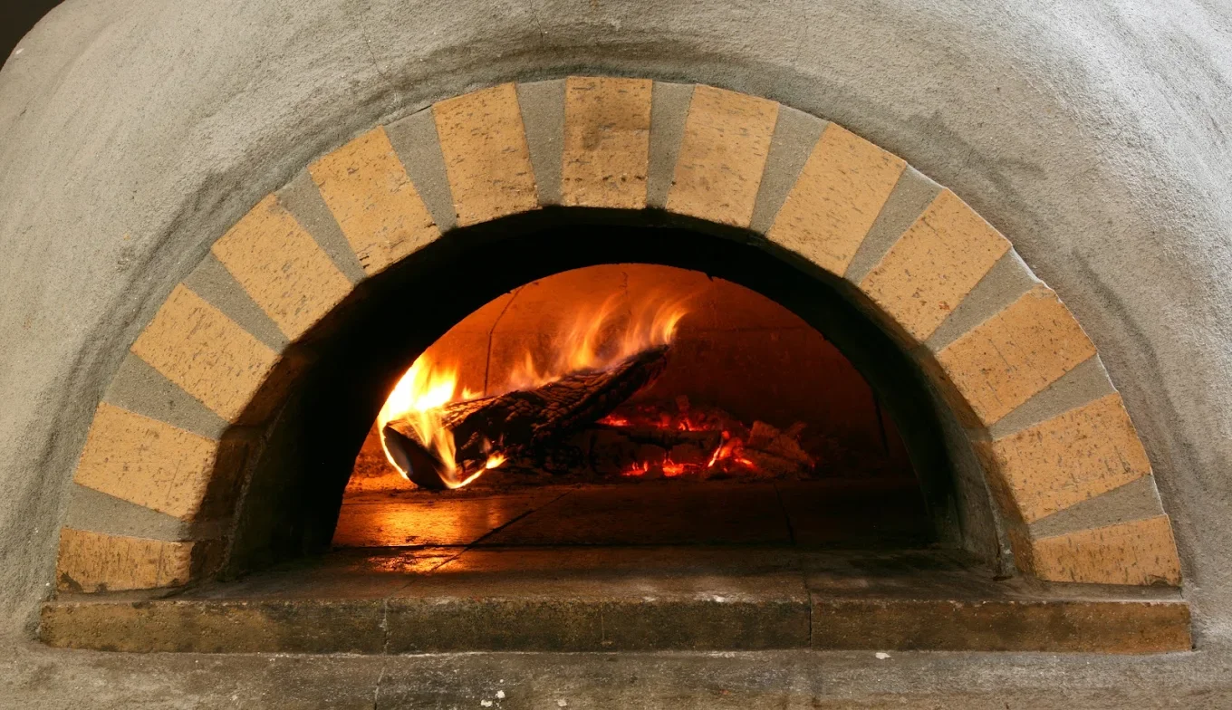 Wood burning inside an oven with a brick arch opening.