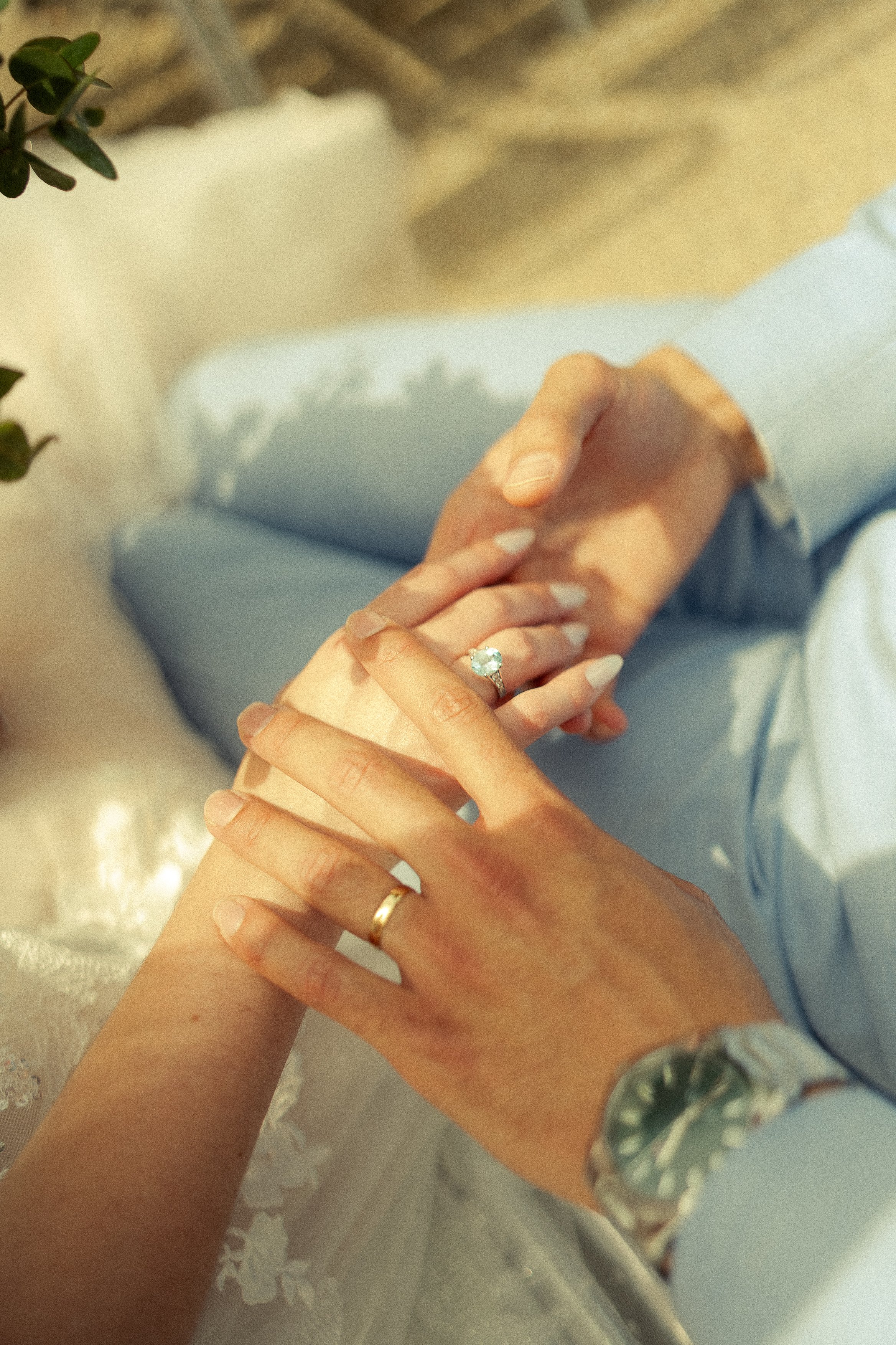 Close-up of a man and woman holding hands, with wedding rings on their fingers, during a wedding ceremony or romantic moment.