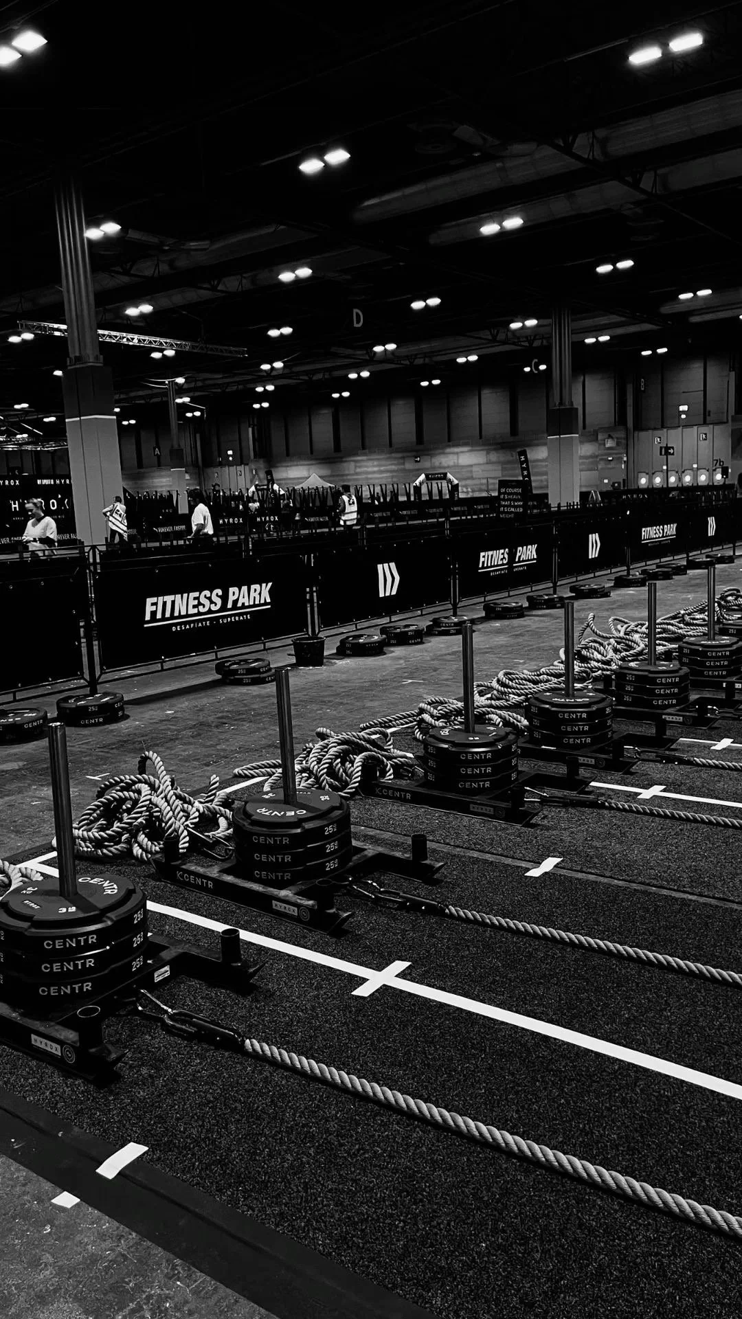 Indoor gym with battle ropes, weight plates, and lanes marked on the floor for fitness training.