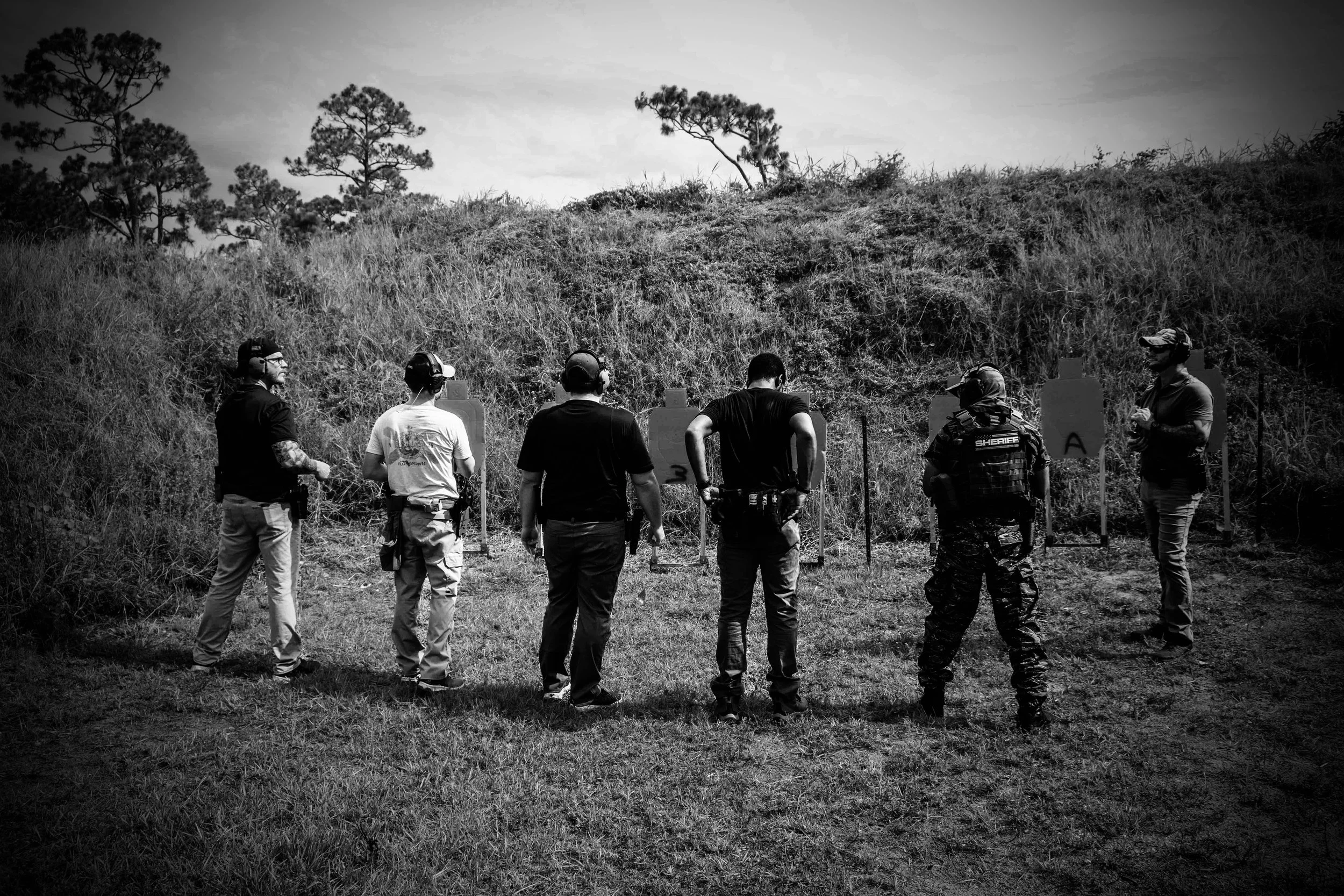 Group of people looking at shooting targets outdoors.