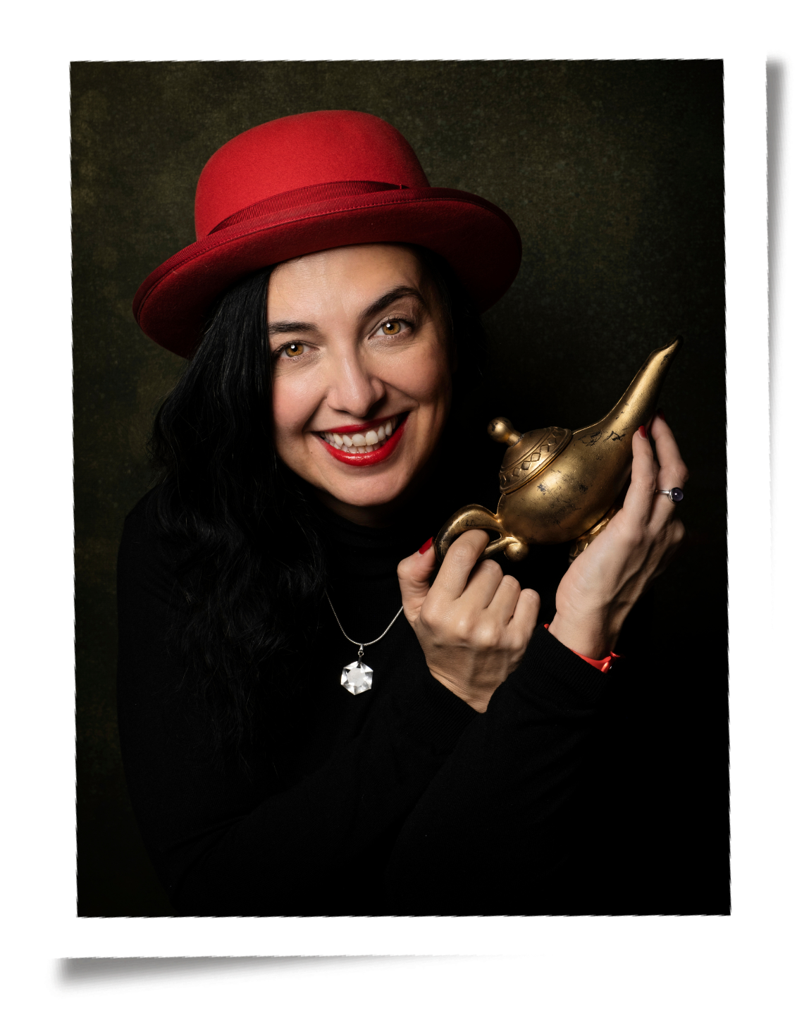 Elena, a woman with black hair, red lipstick, and a red hat, holding a brass magic lamp and smiling.