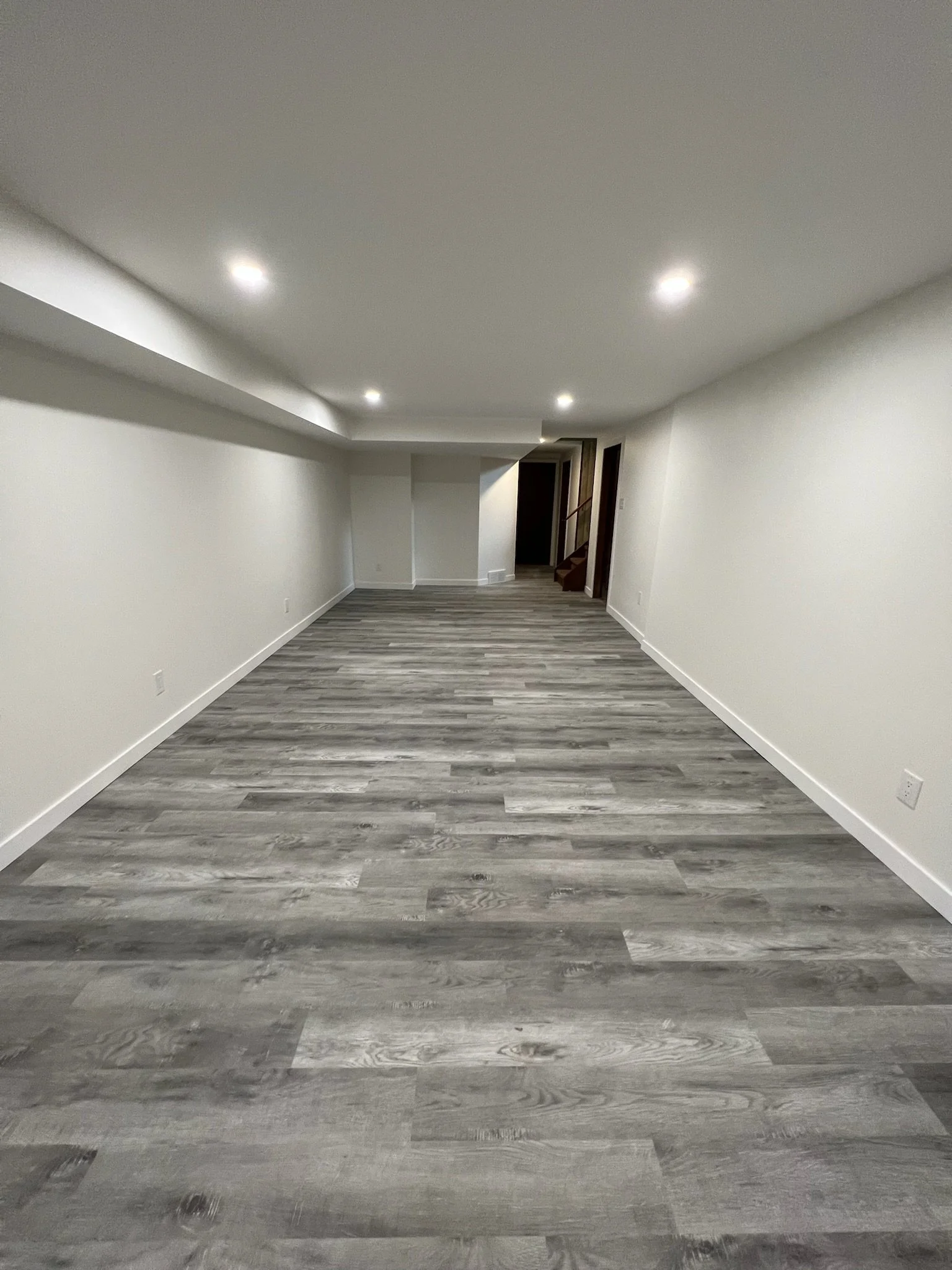 Completed basement renovation in West London by Burcon Construction, showcasing modern vinyl flooring and improved functionality.