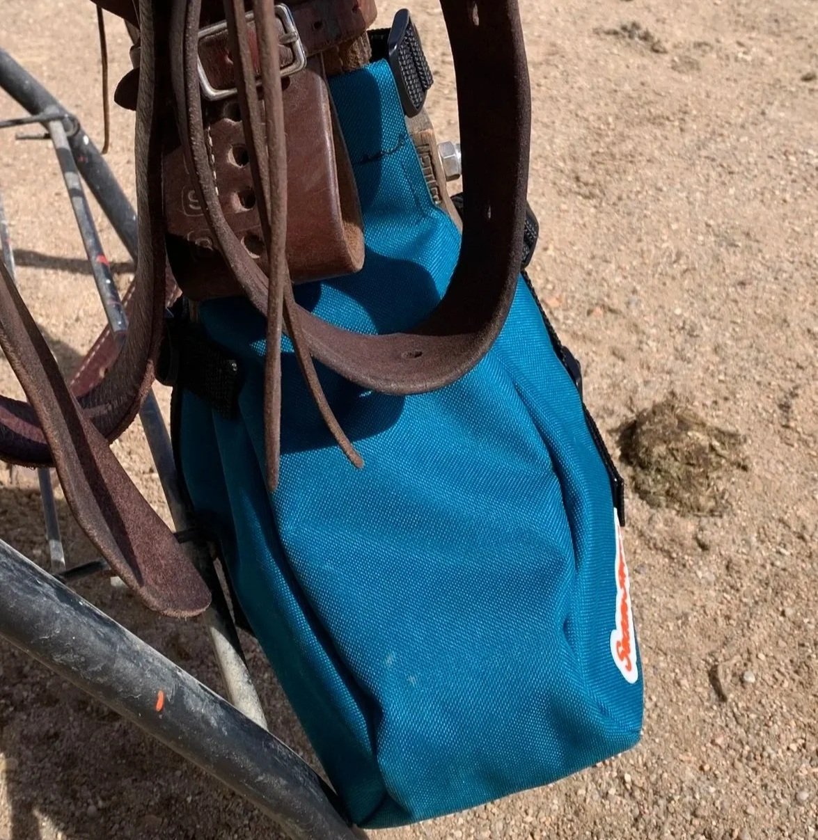 A turquoise Saddle Slipper attached to a stirrup and saddle sitting on a stand.