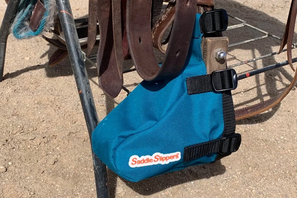 A turquoise Saddle Slipper attached to a stirrup and saddle sitting on a stand.