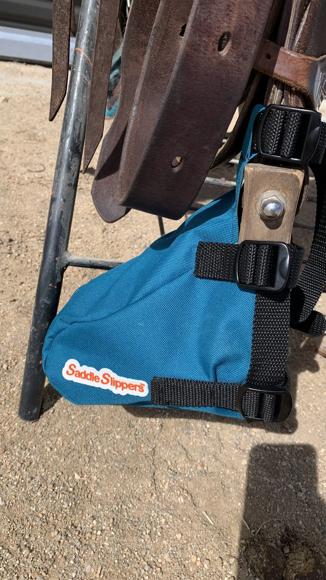 A turquoise Saddle Slipper attached to a stirrup and saddle sitting on a stand.