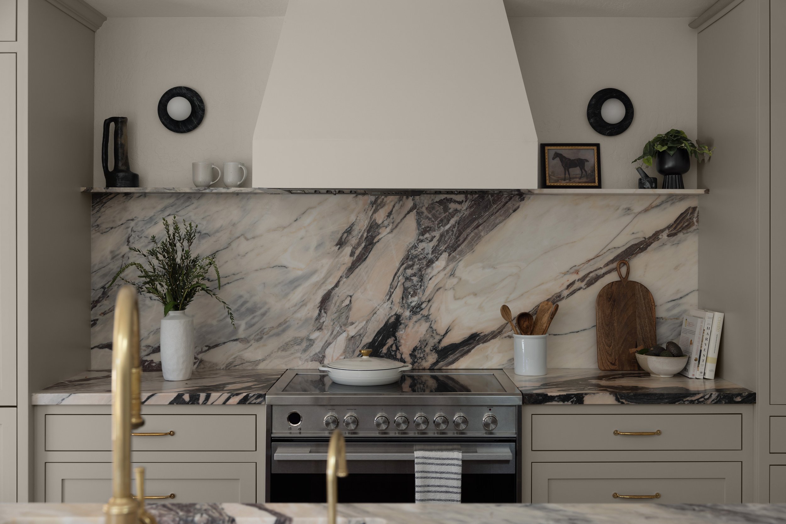 Elegant kitchen remodel with full-height marble slab backsplash, neutral cabinetry, and warm brass accents designed in the Bay Area.