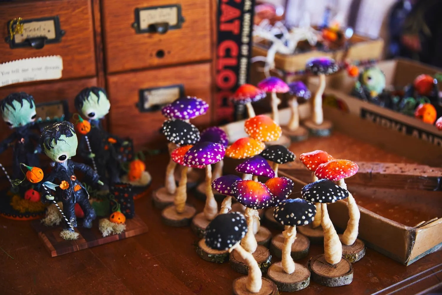 Colorful mushroom and zombie doll Halloween crafts displayed on a wooden table.