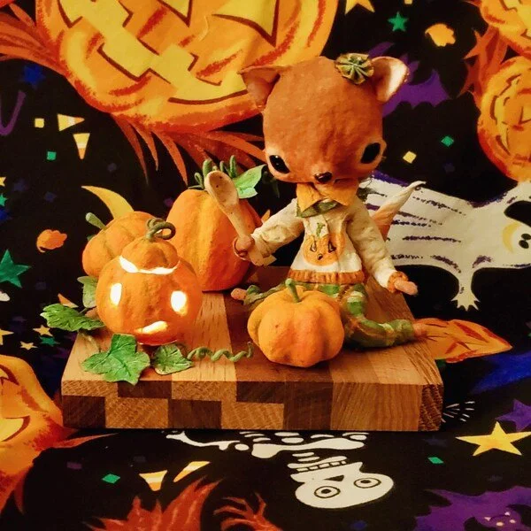 A cute Halloween display featuring a plush animal dressed in fall attire, surrounded by carved pumpkins with glowing faces, on a wooden base with a festive themed background.