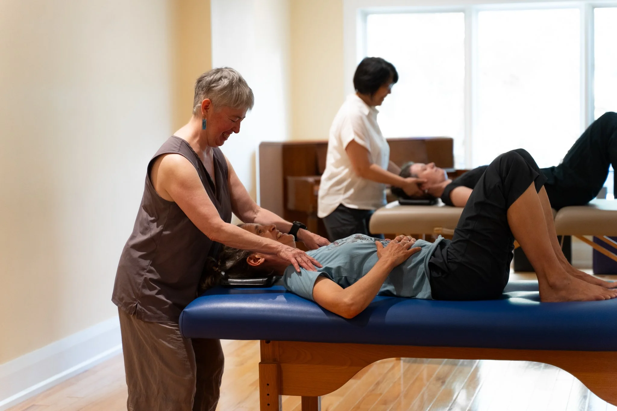 Chiropractors treating patients on massage tables in a wellness center.
