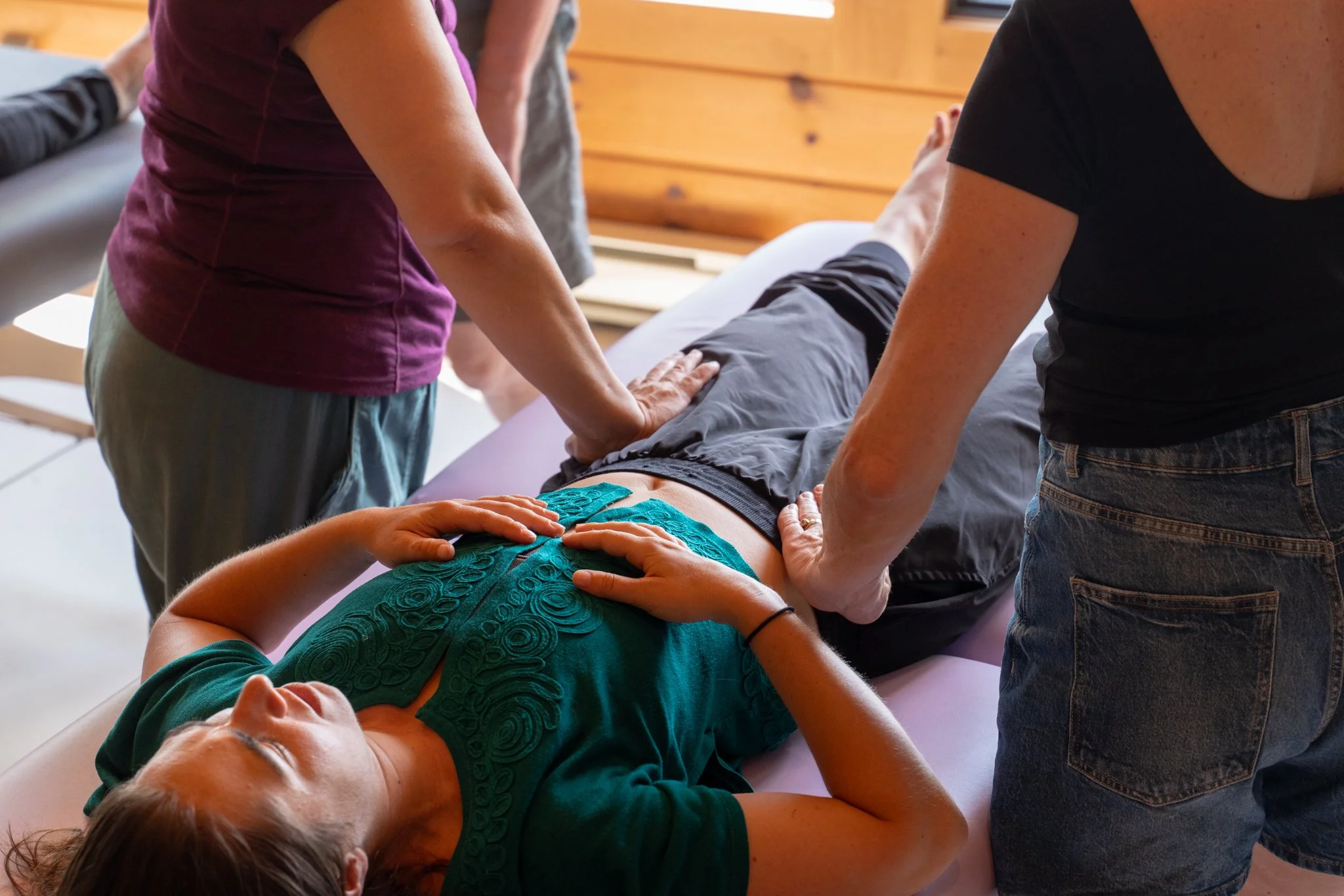 Person lying on a massage table receiving chiropractic care from two practitioners.